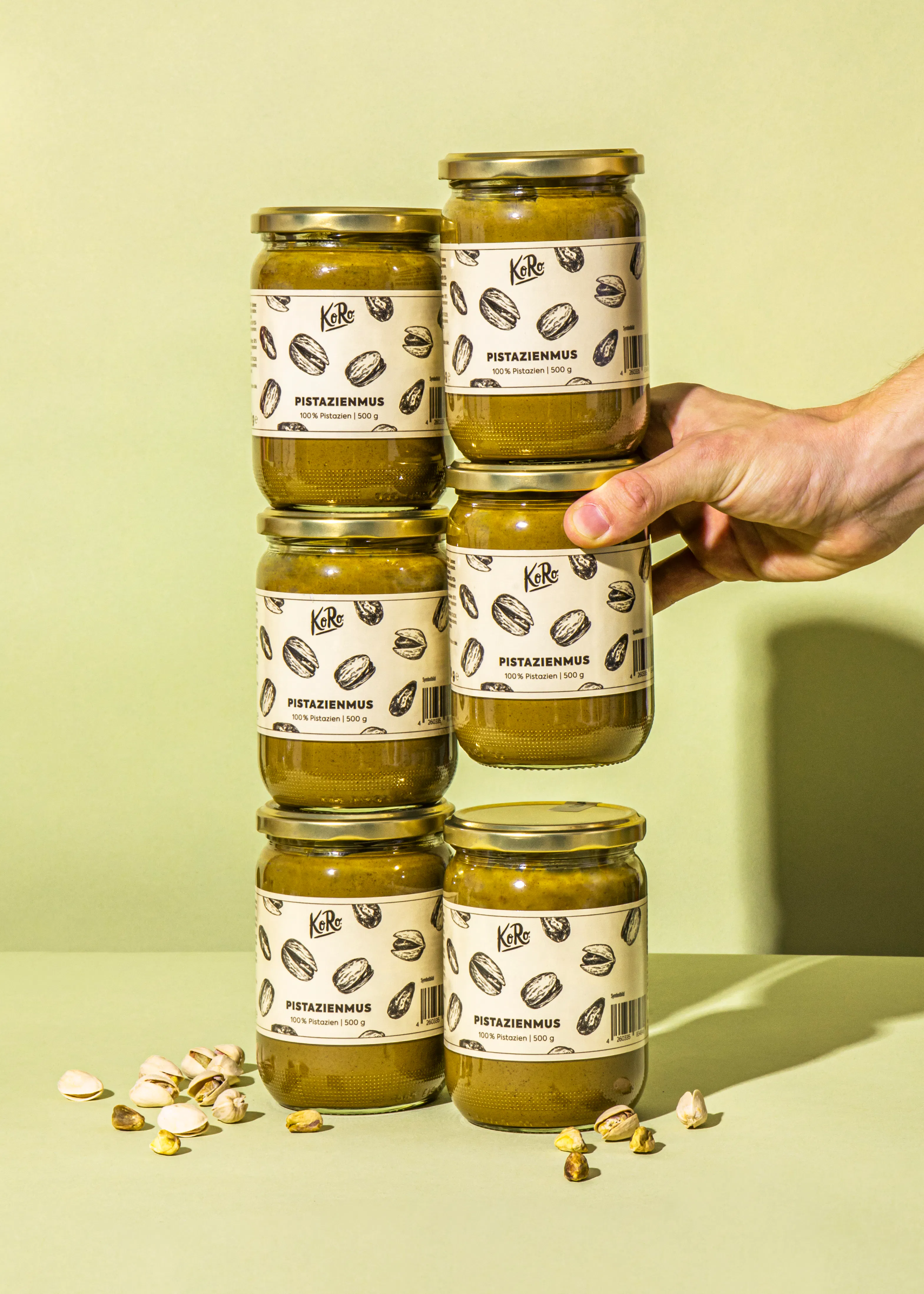 Eine Person hält sechs Gläser pistazienmus in der Hand