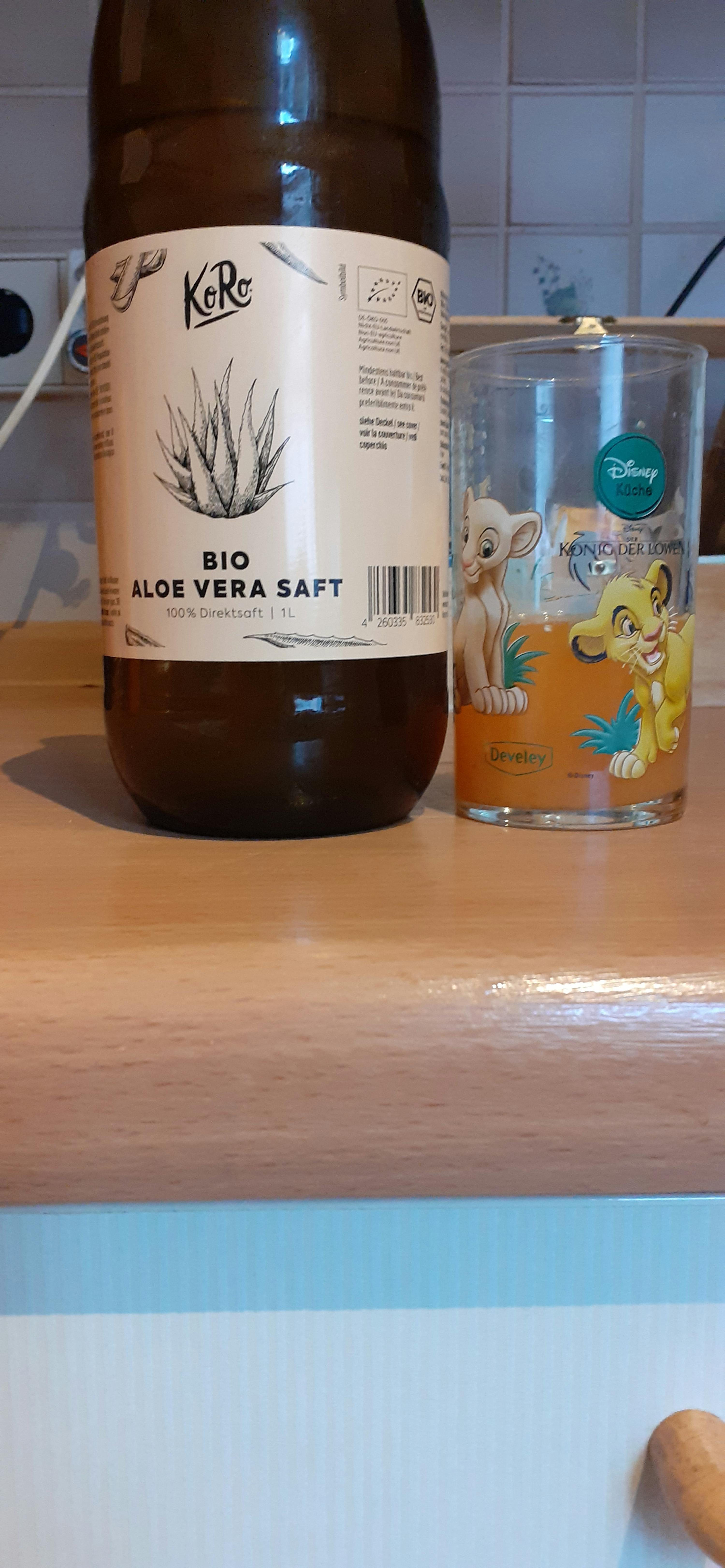 a bottle of aloe vera soft next to a disney glass