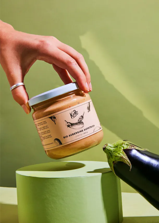 eine Person hält ein Glas mit der Aufschrift " bio aubergine aufstrich "