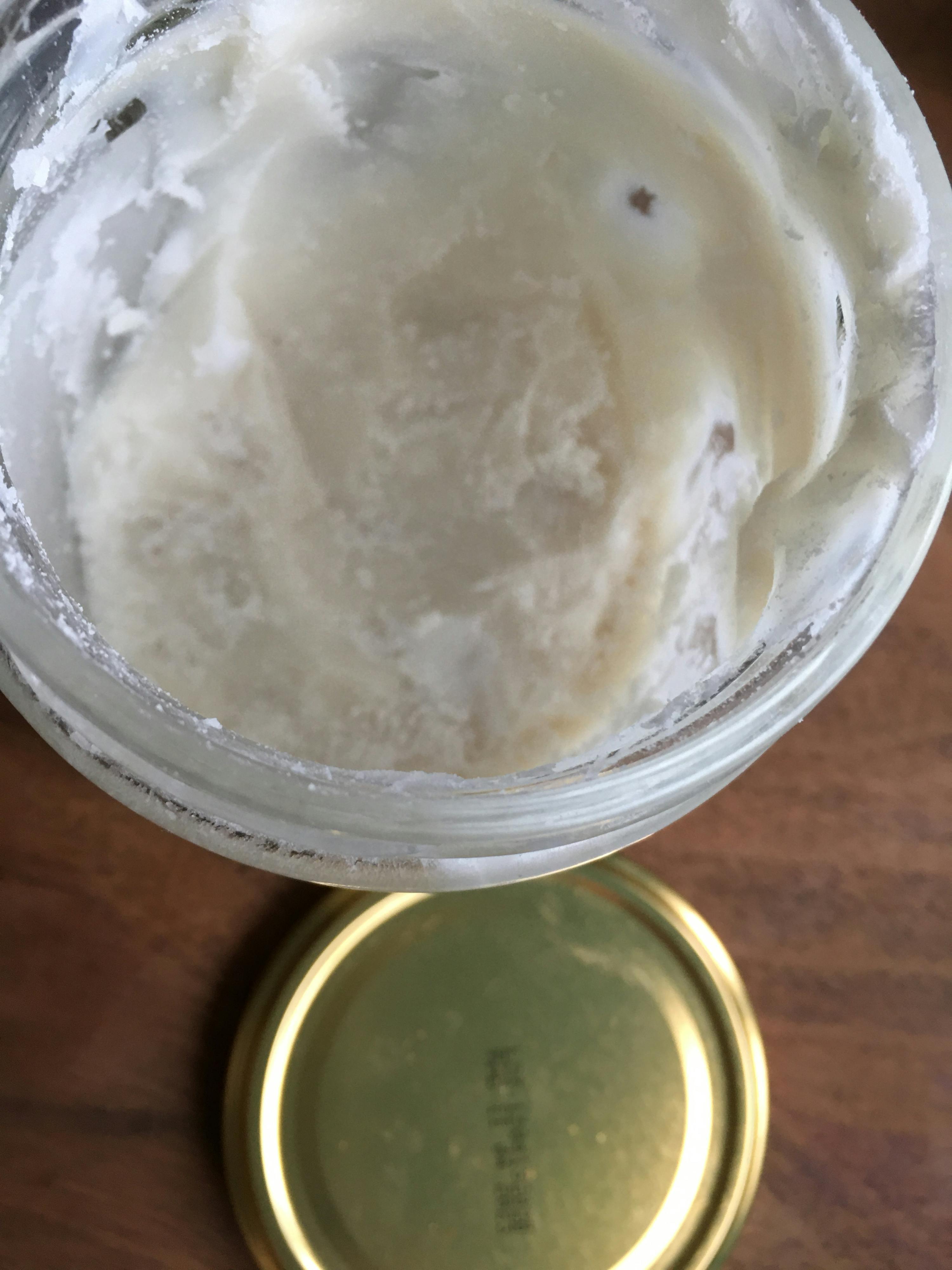 ein Glas mit einer weißen Flüssigkeit in ihm und einem goldenen Deckel