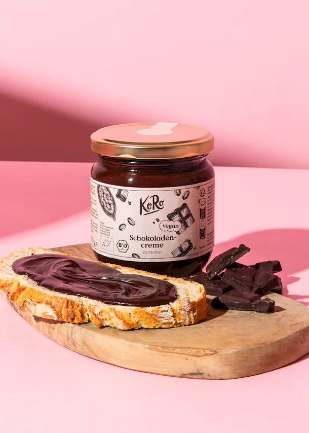 une bouteille de crème au chocolat avec une tranche de pain sur une planche à découper en bois