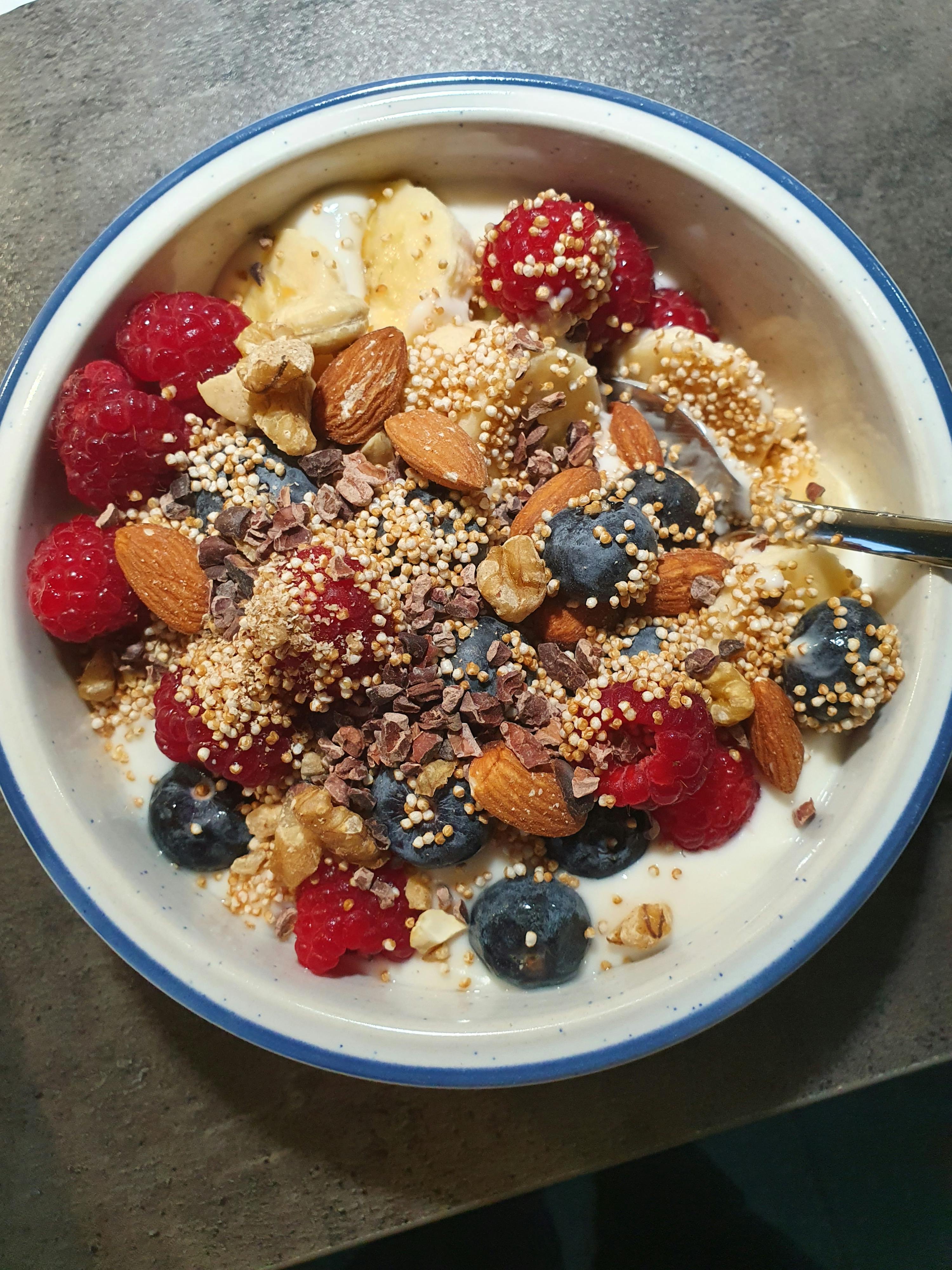 eine schüssel mit joghurt und beeren mit einem löffel darin