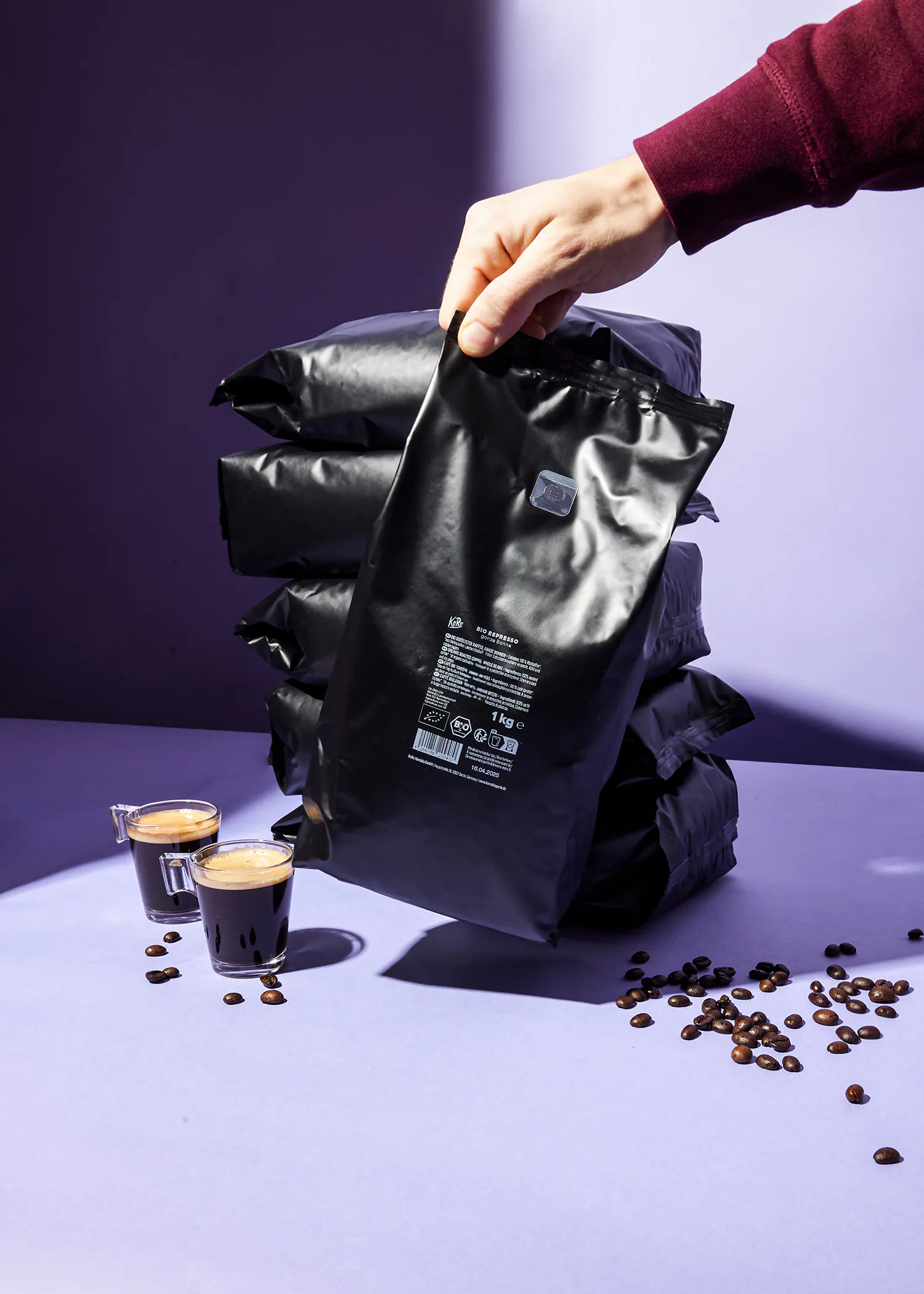 une personne tient un sac de café à côté d' un tas de sacs de café