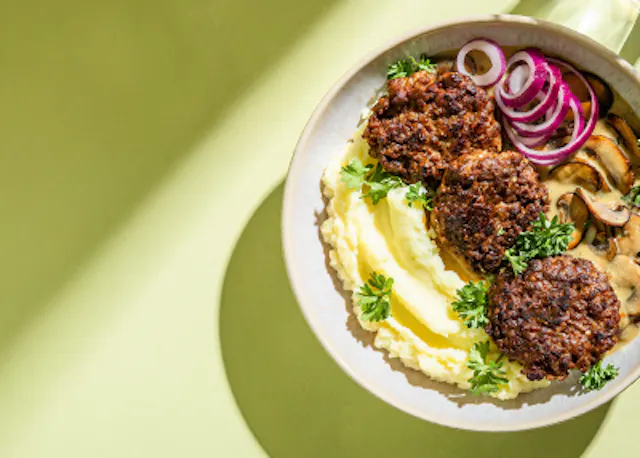 a plate of food with mashed potatoes meatballs onions and mushrooms