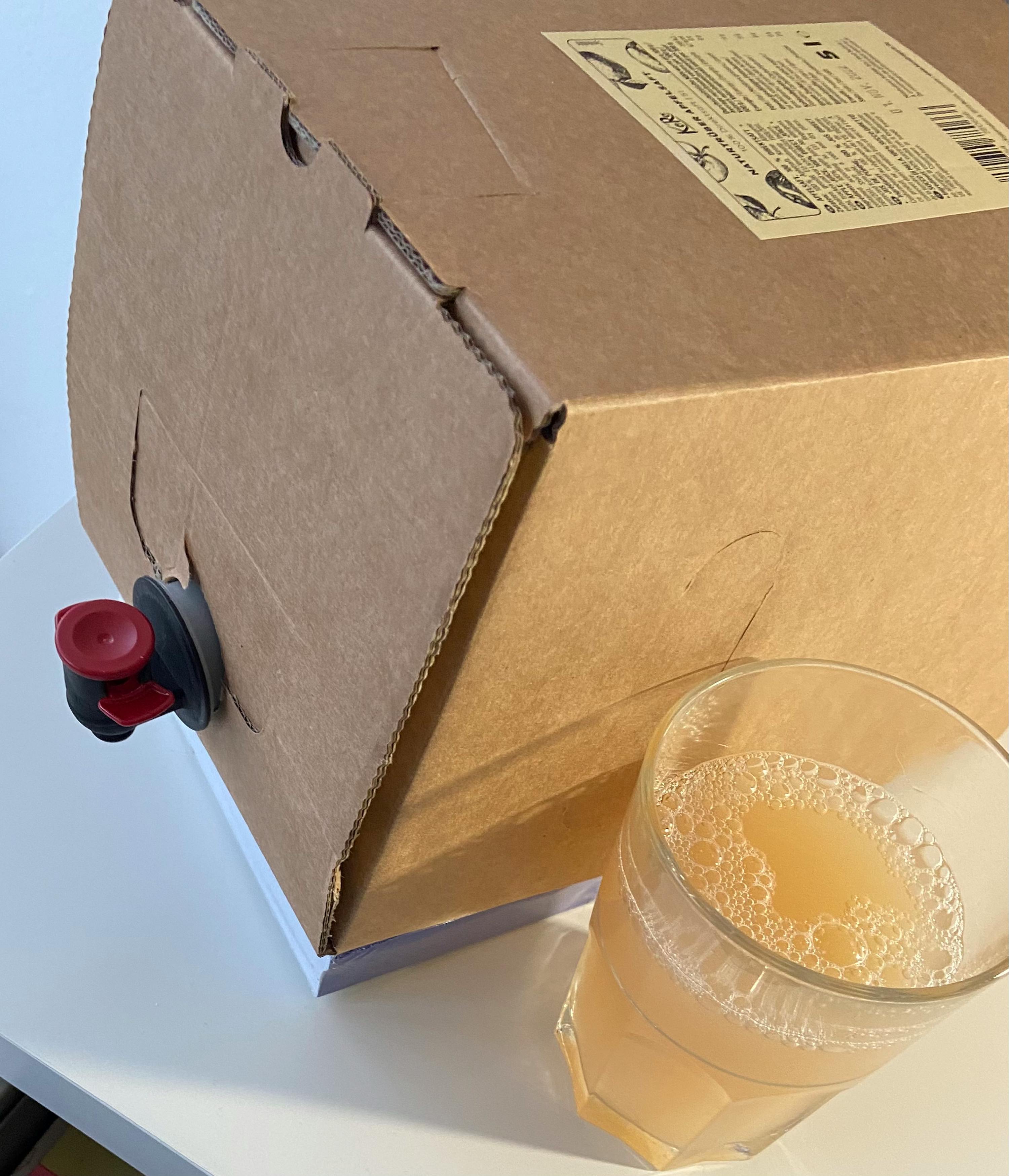 une boîte en carton avec un robinet à côté d' un verre de jus