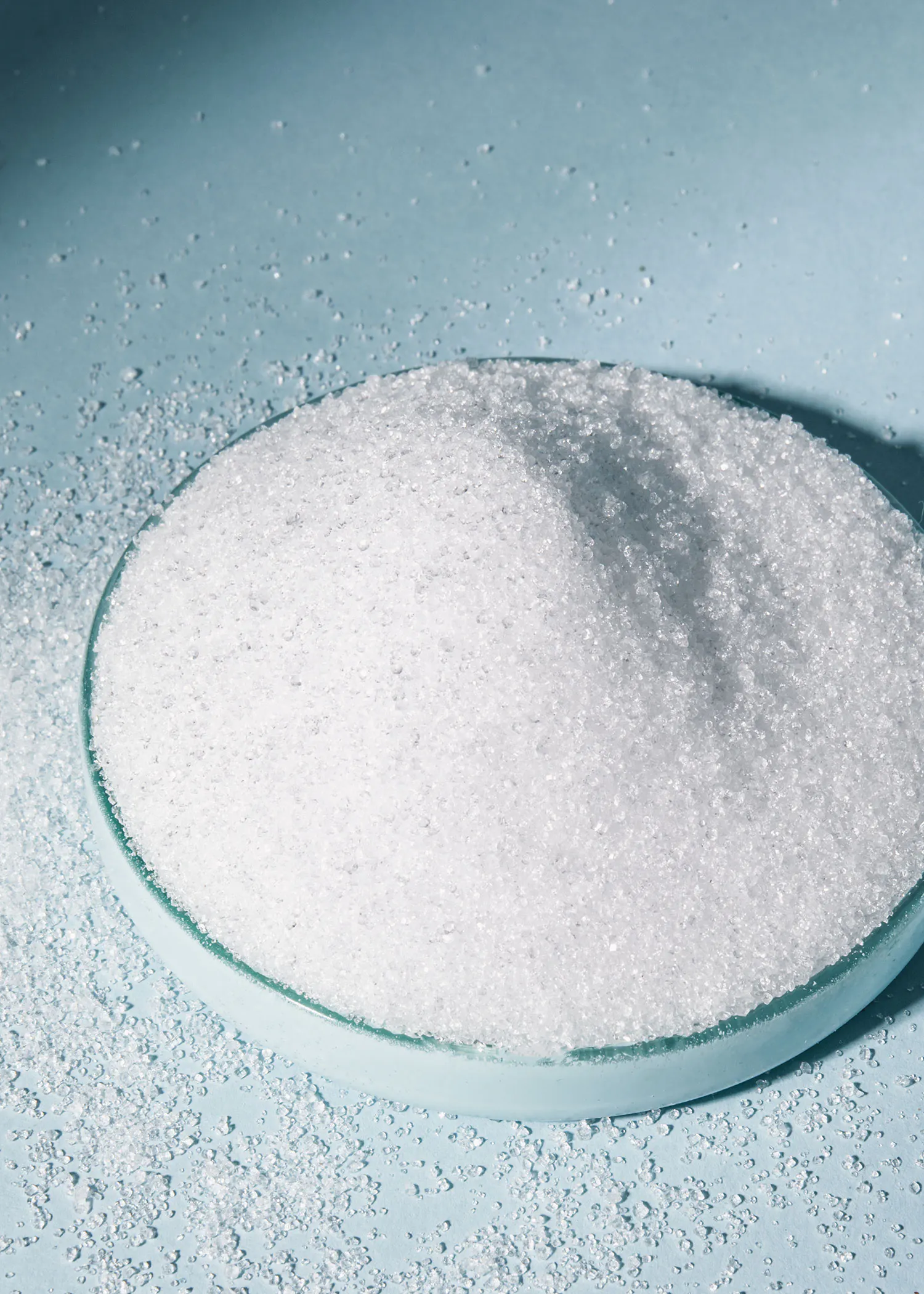 a glass bowl filled with white powder on a blue surface