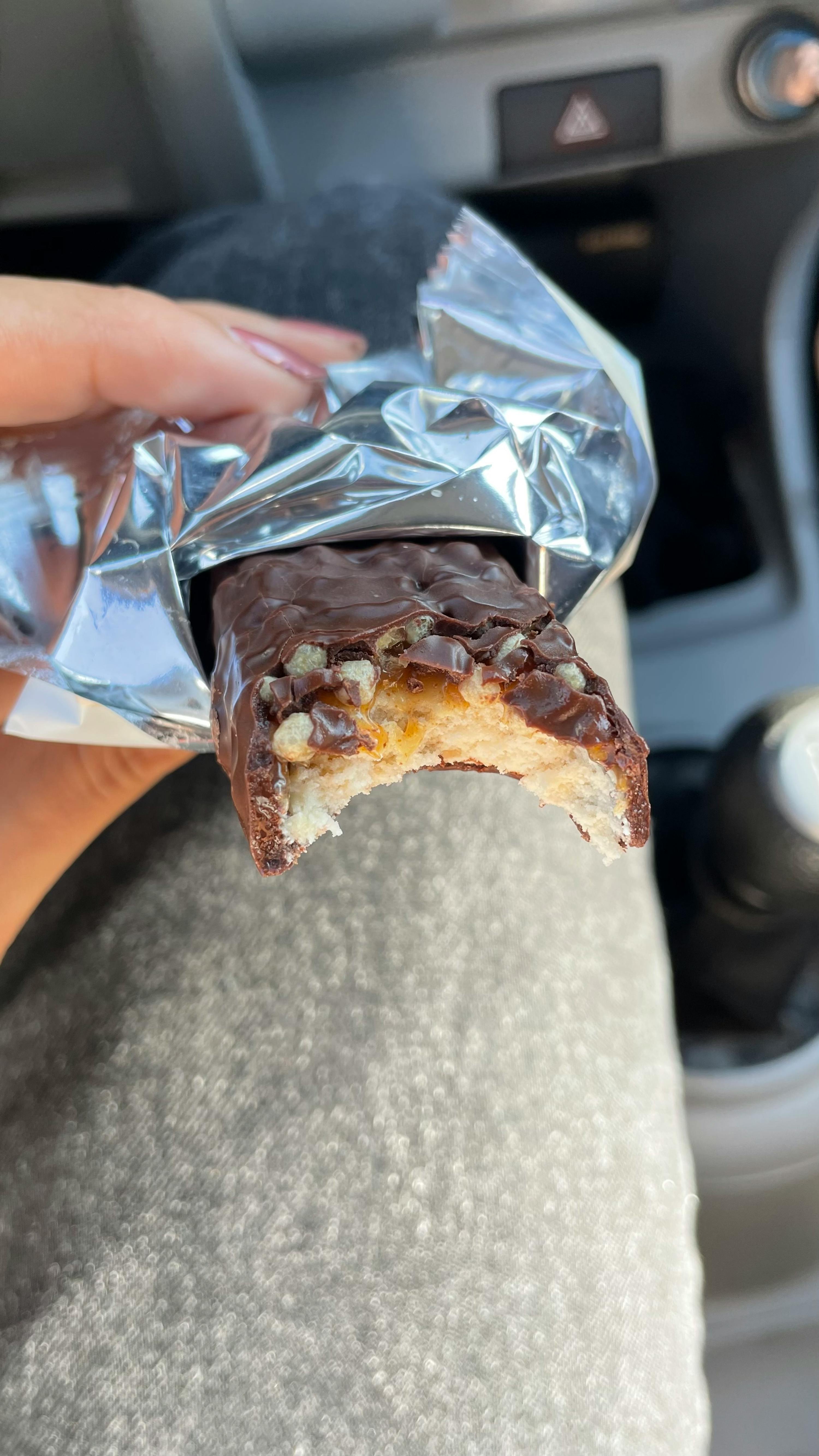 una persona tiene in mano una barretta di cioccolato con una fetta mancante