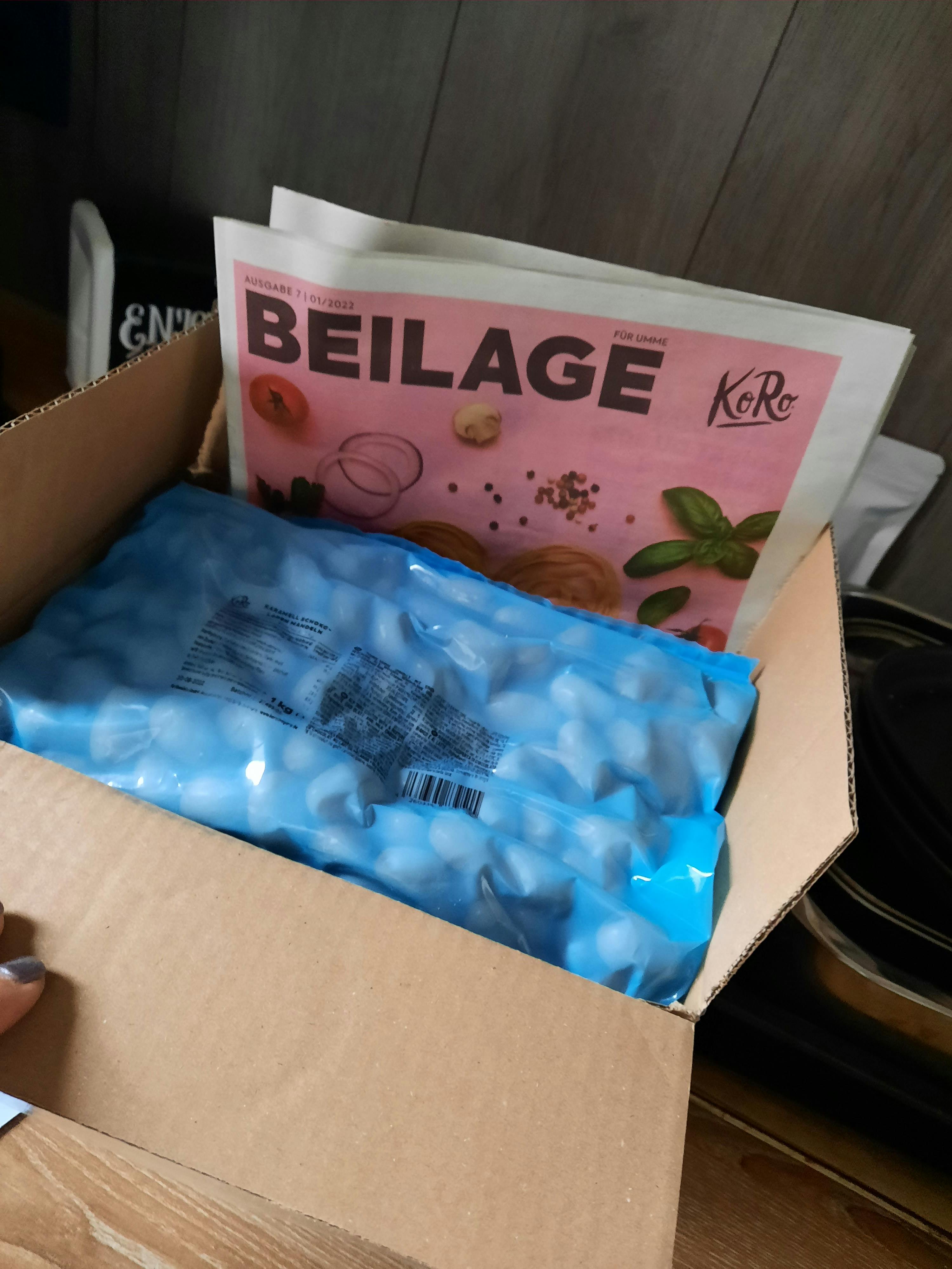 une boîte en carton avec un sac bleu à côté d' une feuille de papier avec le titre beilage