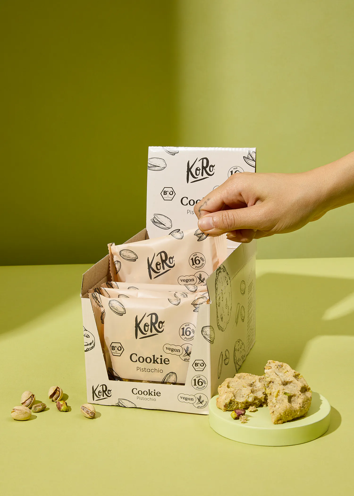 Eine Person greift nach einem Keks aus einer Koro-Box