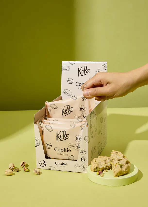 Eine Person greift nach einem Keks aus einer Koro-Box