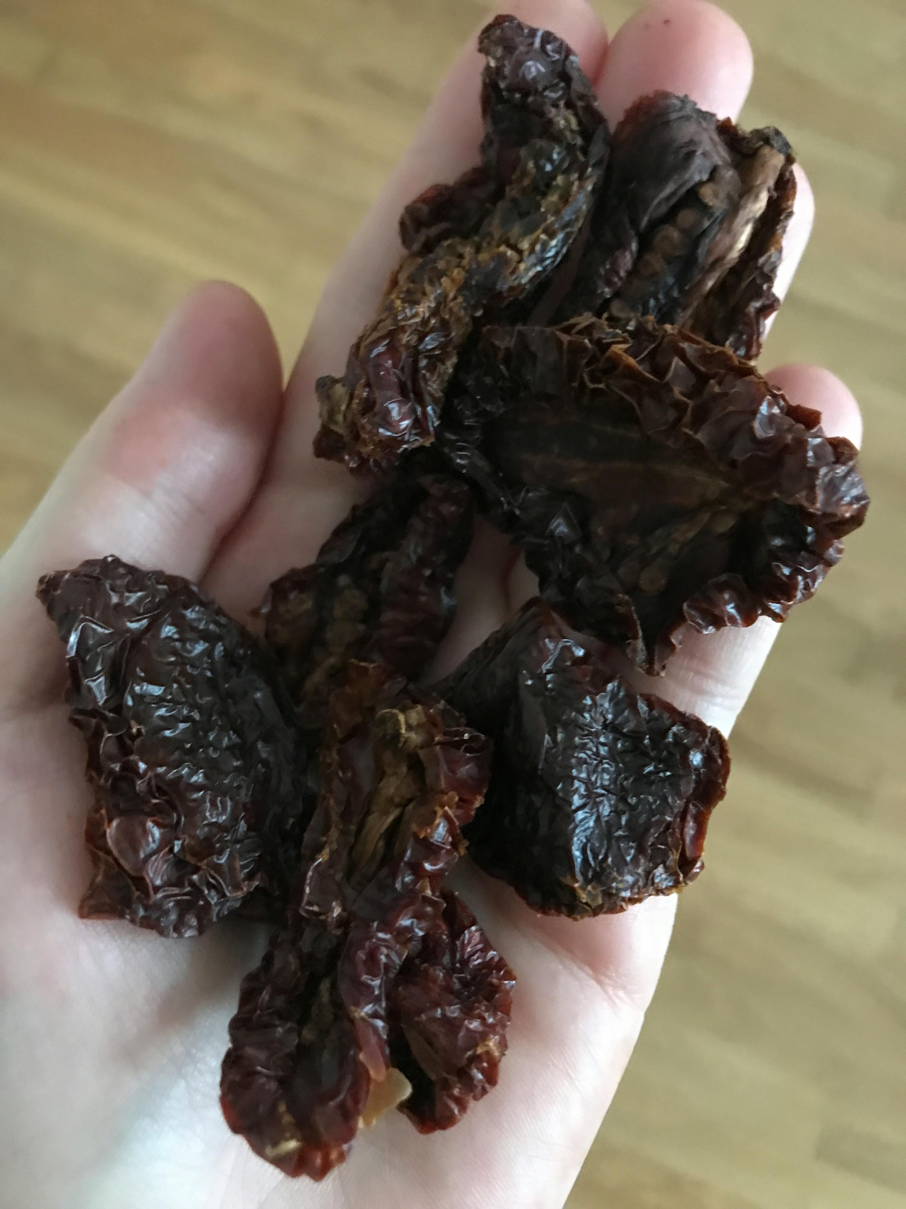 a hand holding a pile of dried tomatoes