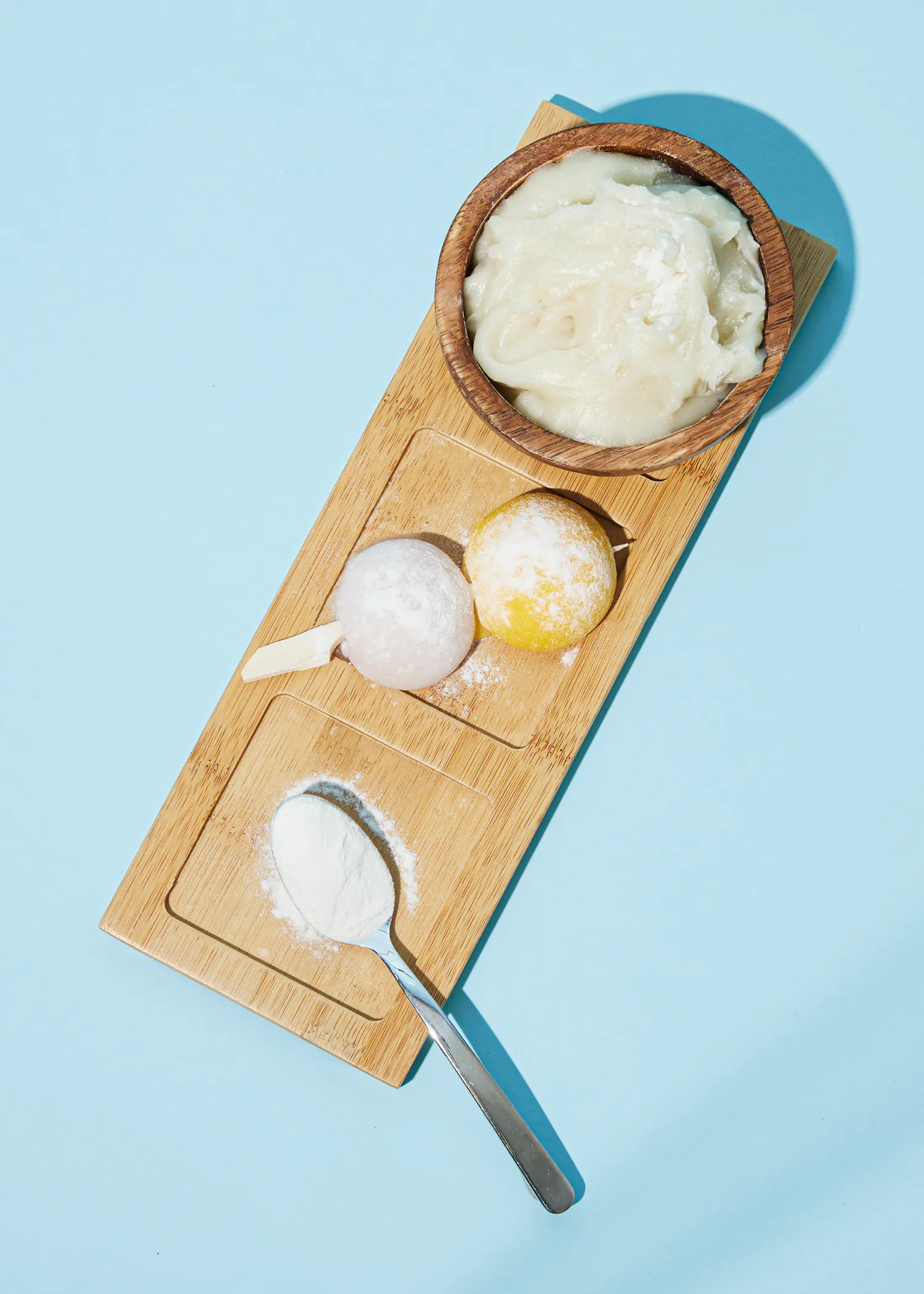 a wooden tray with a bowl of mashed potatoes a lemon and powdered sugar