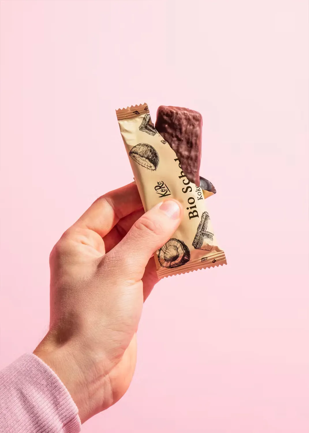 une personne tient une barre de chocolat bio sur fond rose
