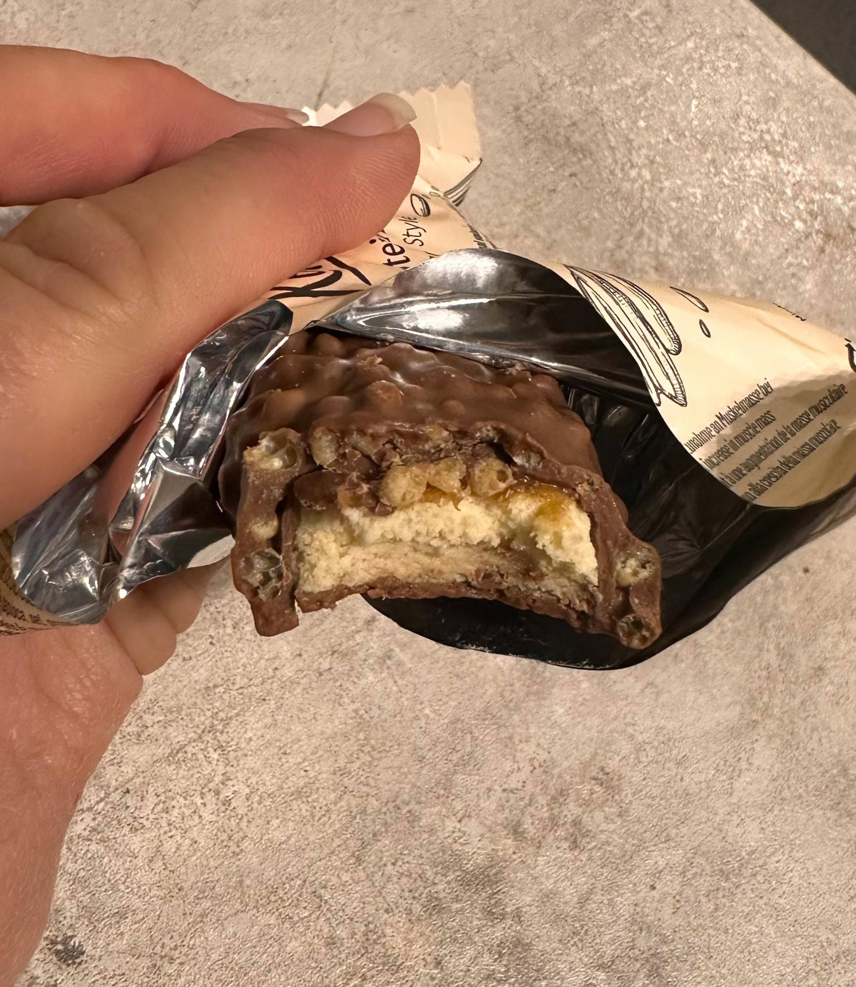 eine Person hält einen Schokoladenriegel mit einem Stück herausgenommen