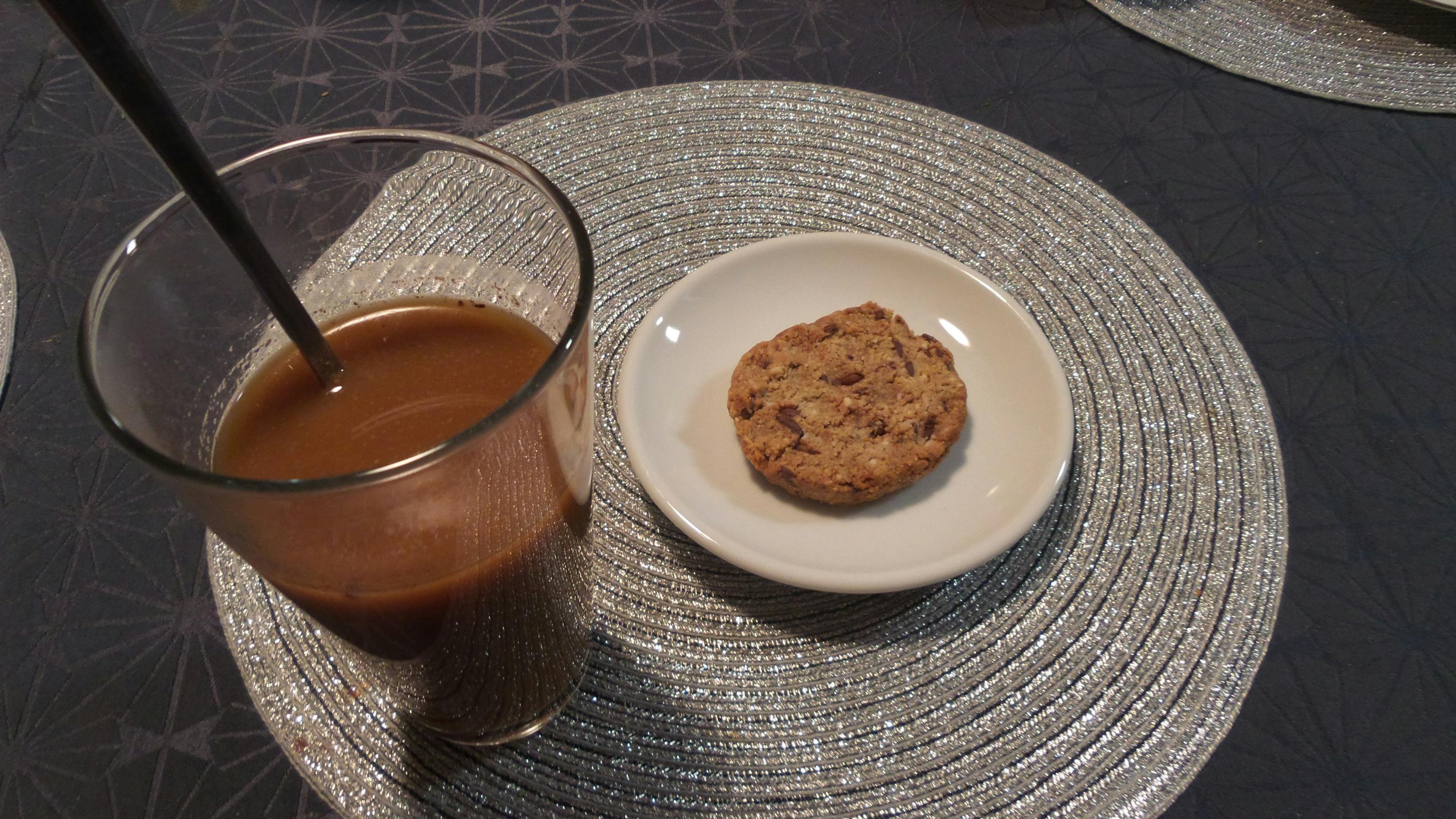 ein Glas Kaffee und ein Schokoladenkeks auf einem Tisch