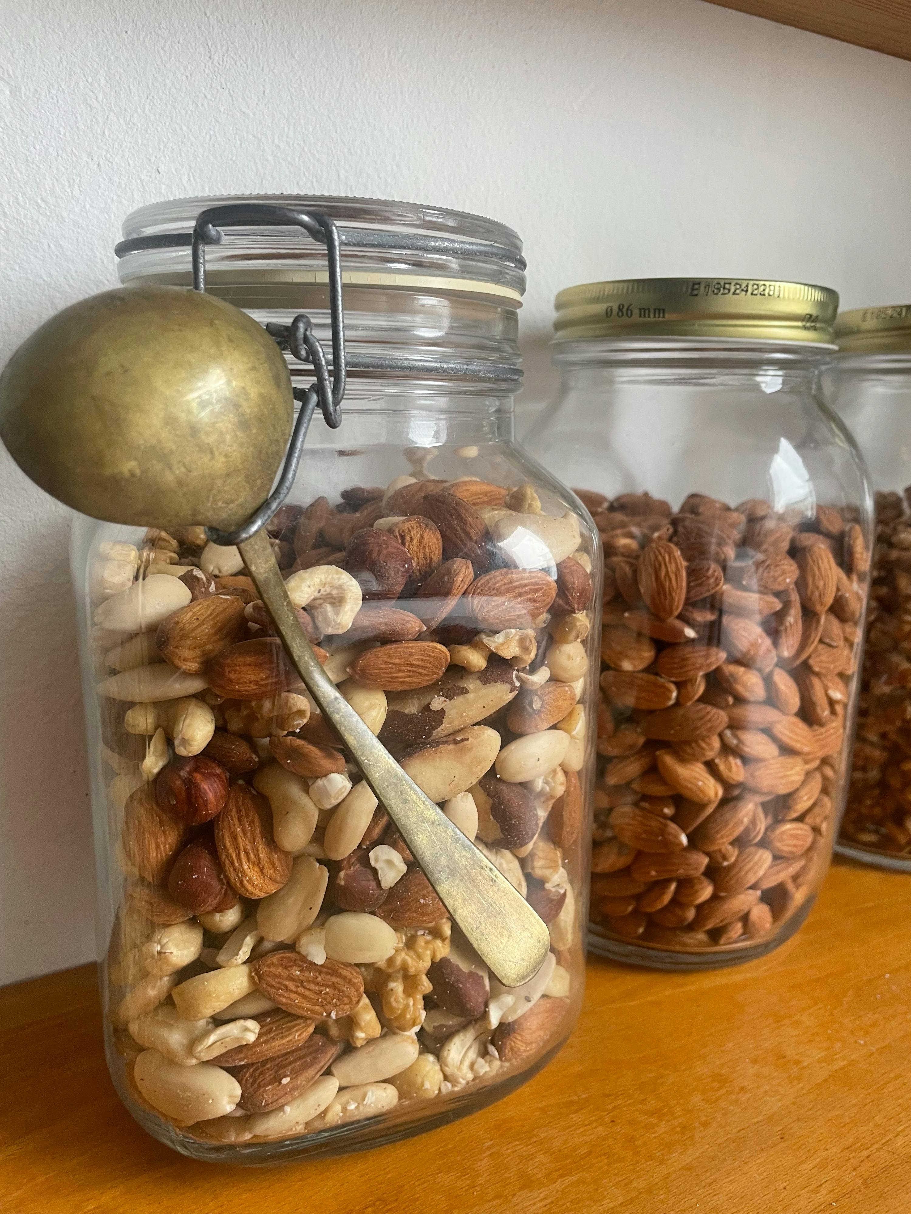 un bocal rempli de noix avec une cuillère à côté