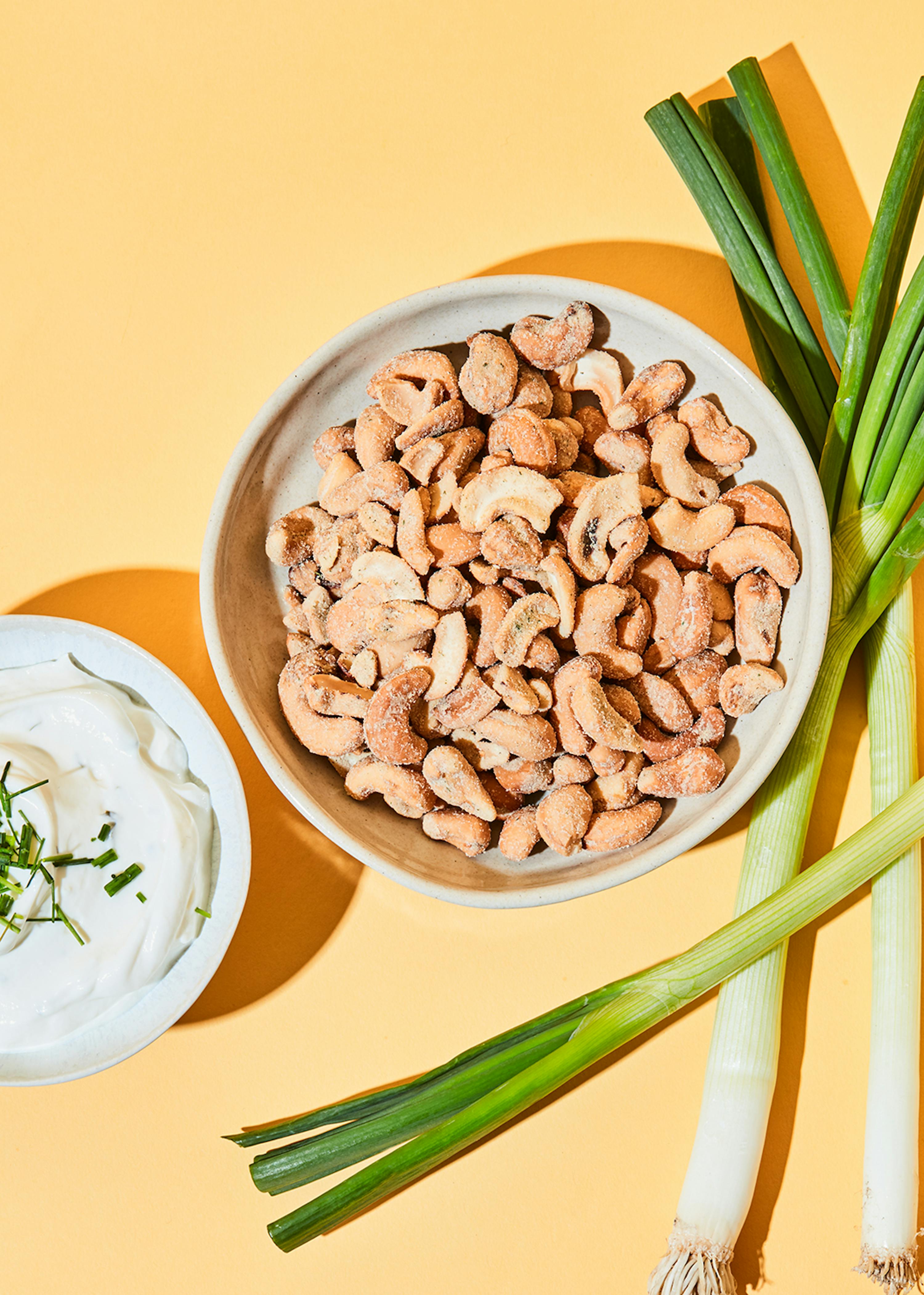un bol de noix de cajou est assis à côté d' une assiette de mayonnaise et d' oignons