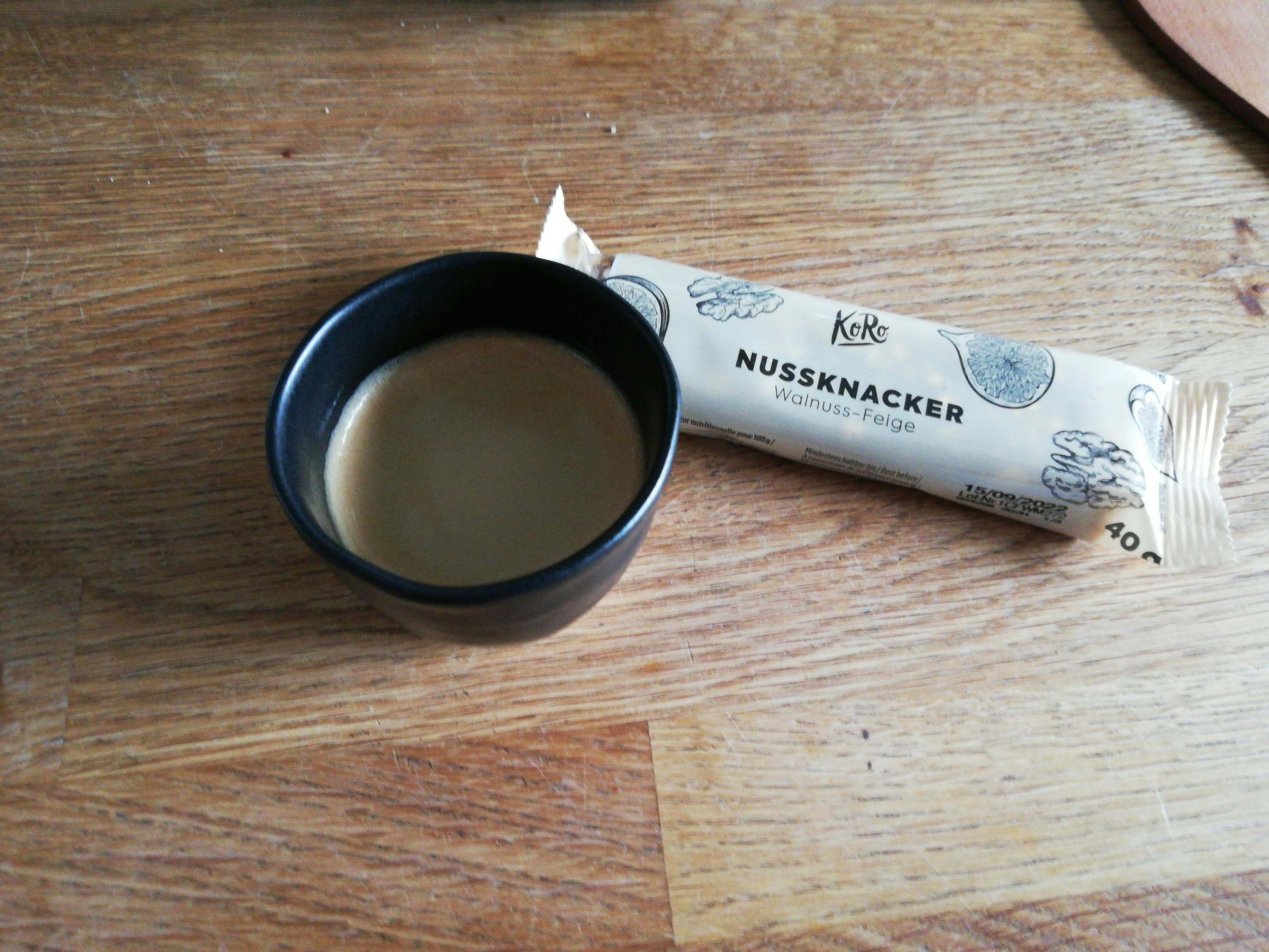 eine kleine tasse kaffee neben einem nussknabber