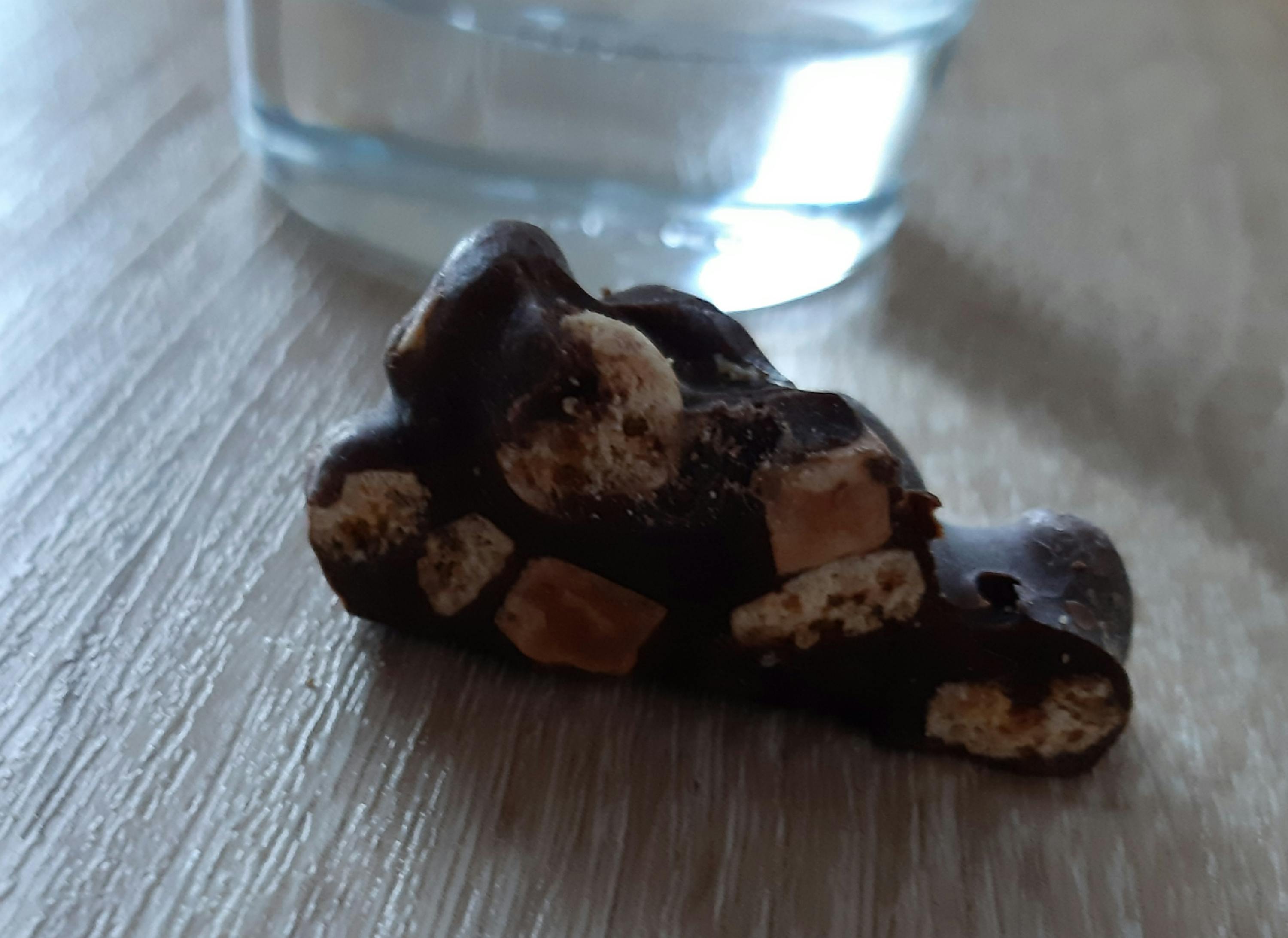 un morceau de chocolat sur une table avec un verre d' eau en arrière-plan