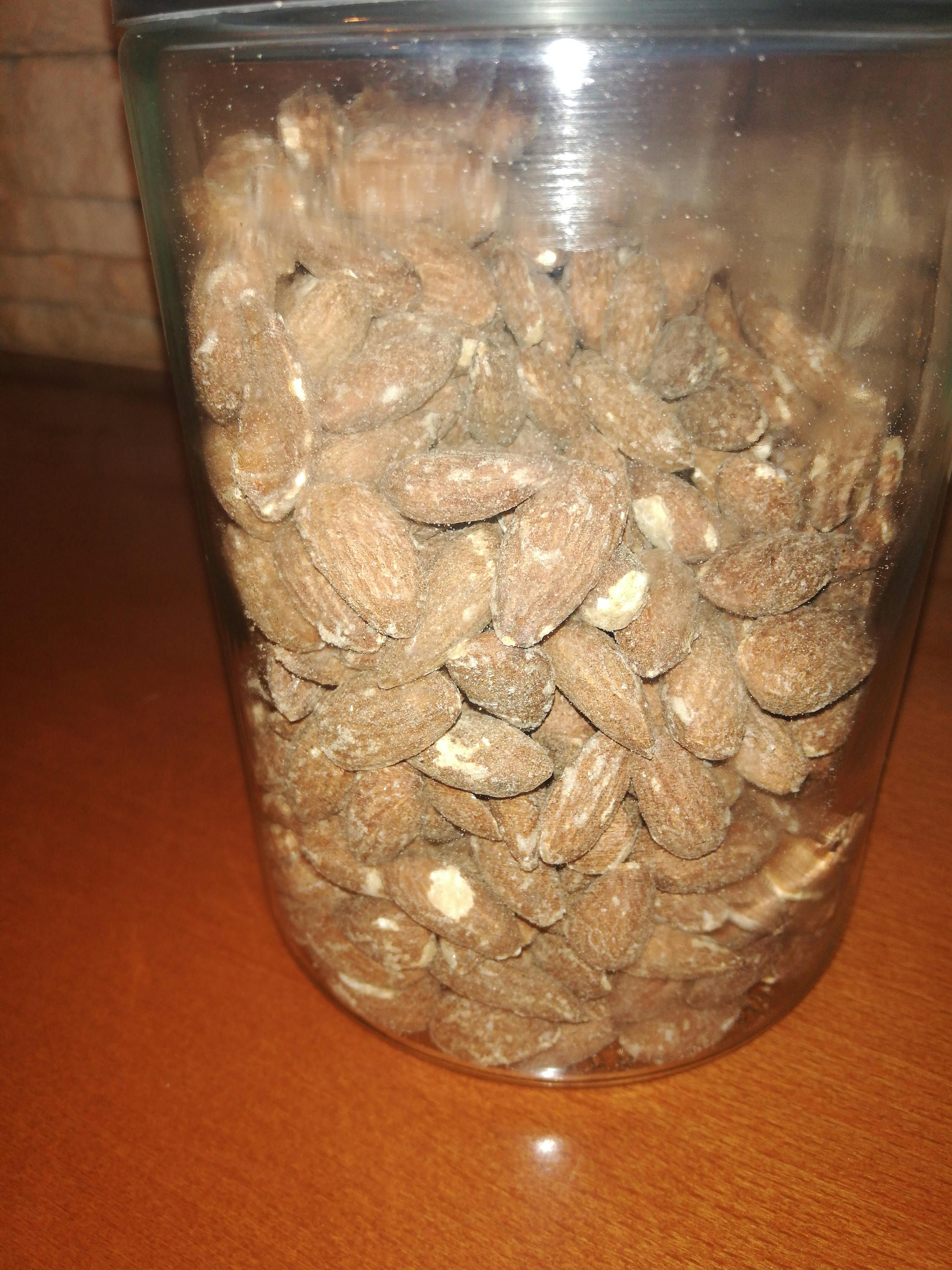 a glass jar filled with almonds on a wooden table