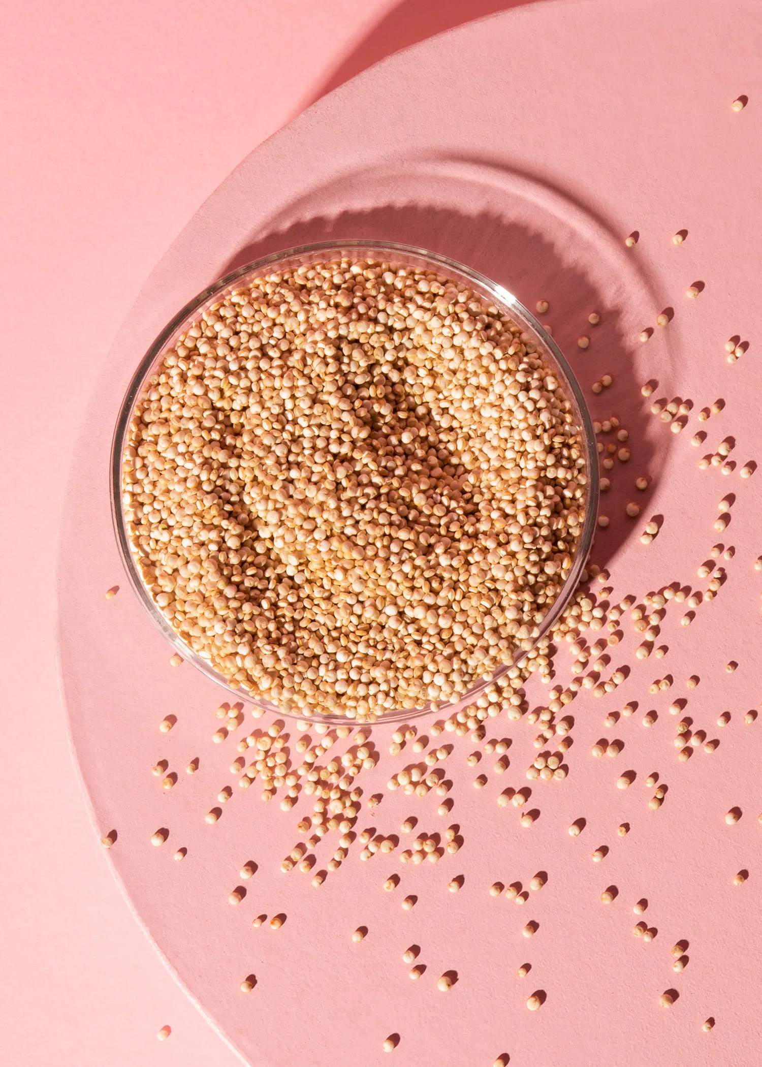 un bol en verre rempli de graines sur une surface rose