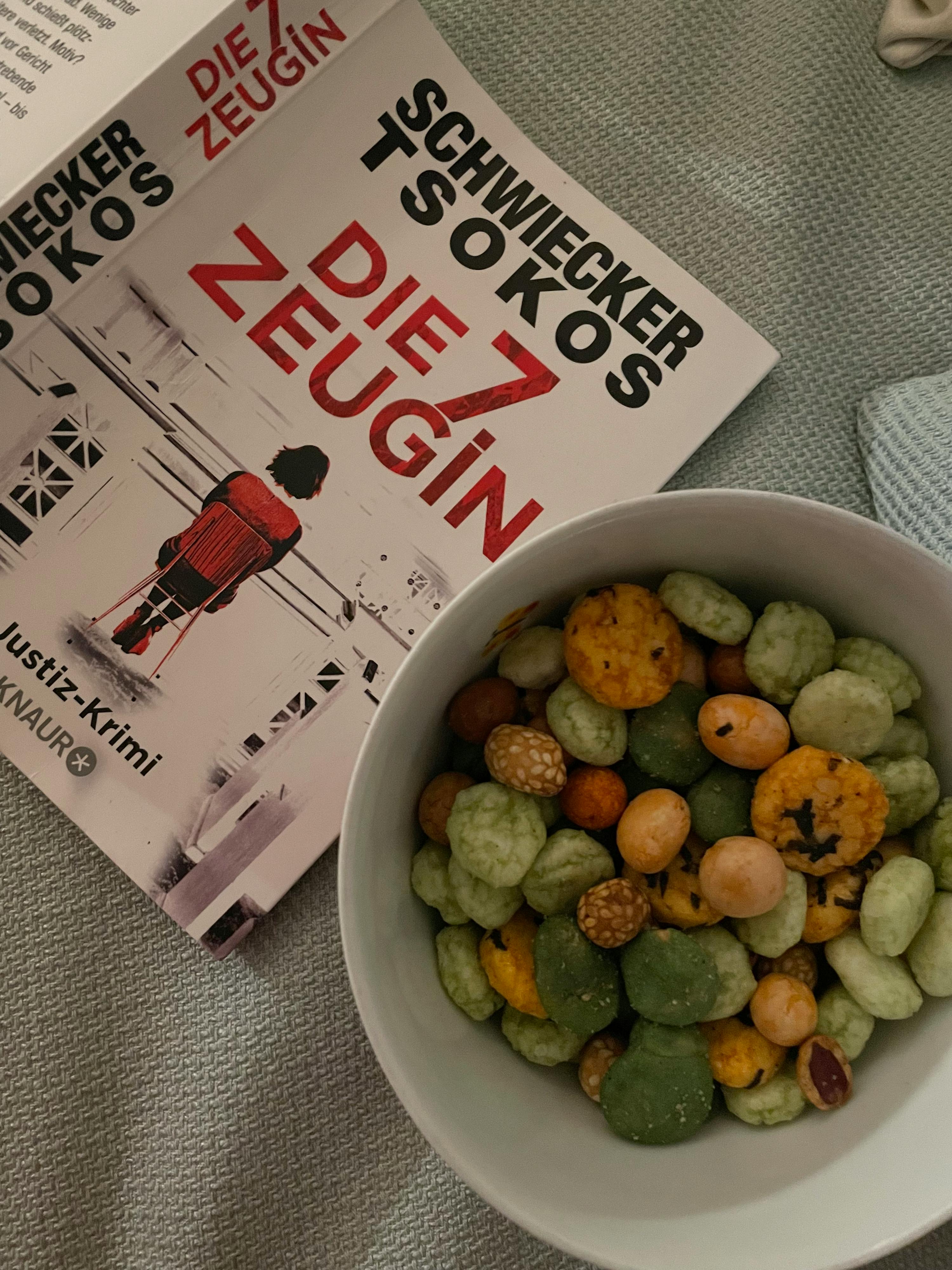 a bowl of nuts sits next to a book by schwecker tsokos
