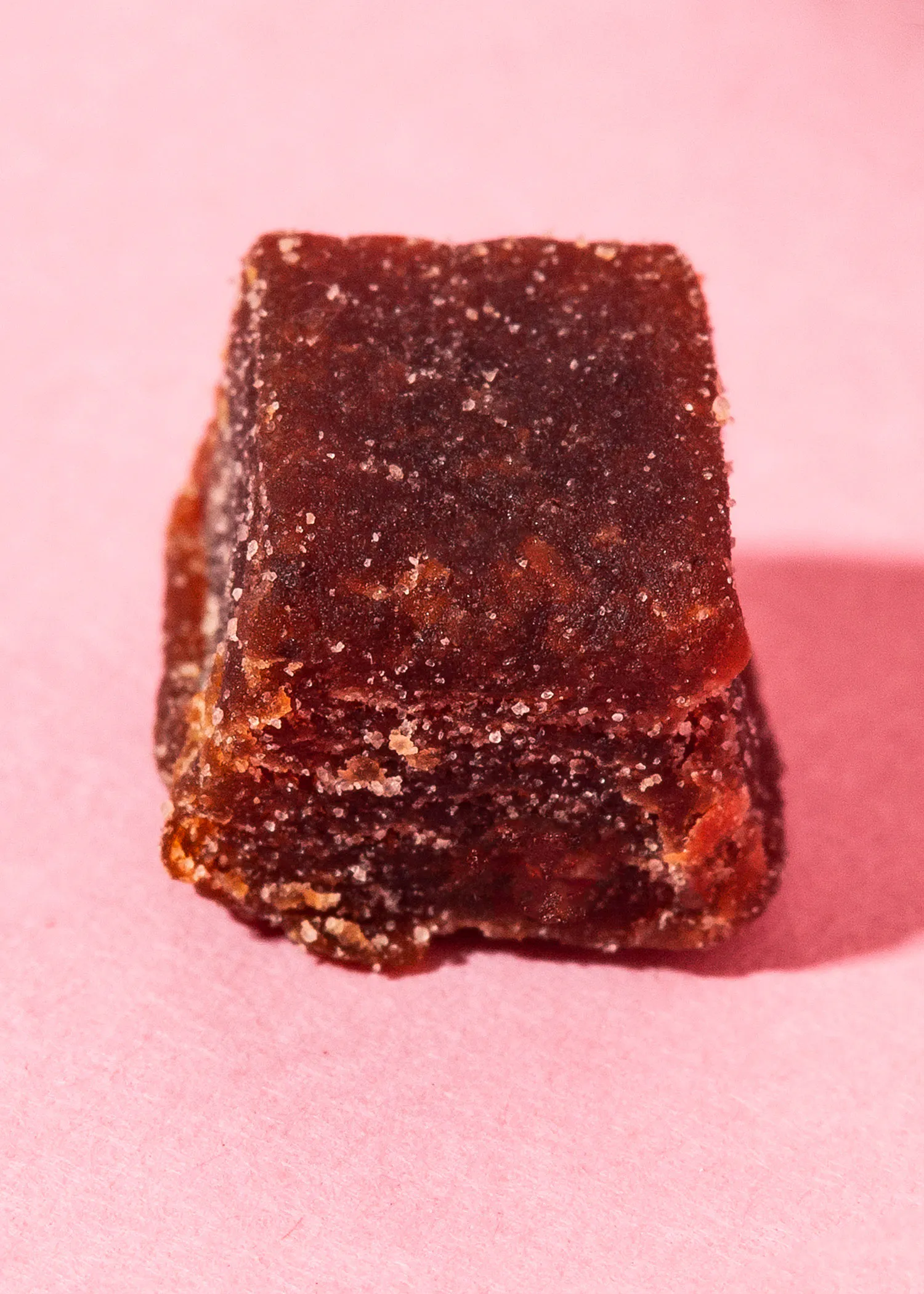 a close up of a piece of candy on a pink surface