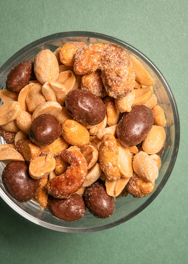 un bol en verre rempli de noix de cajou et de cacahuètes