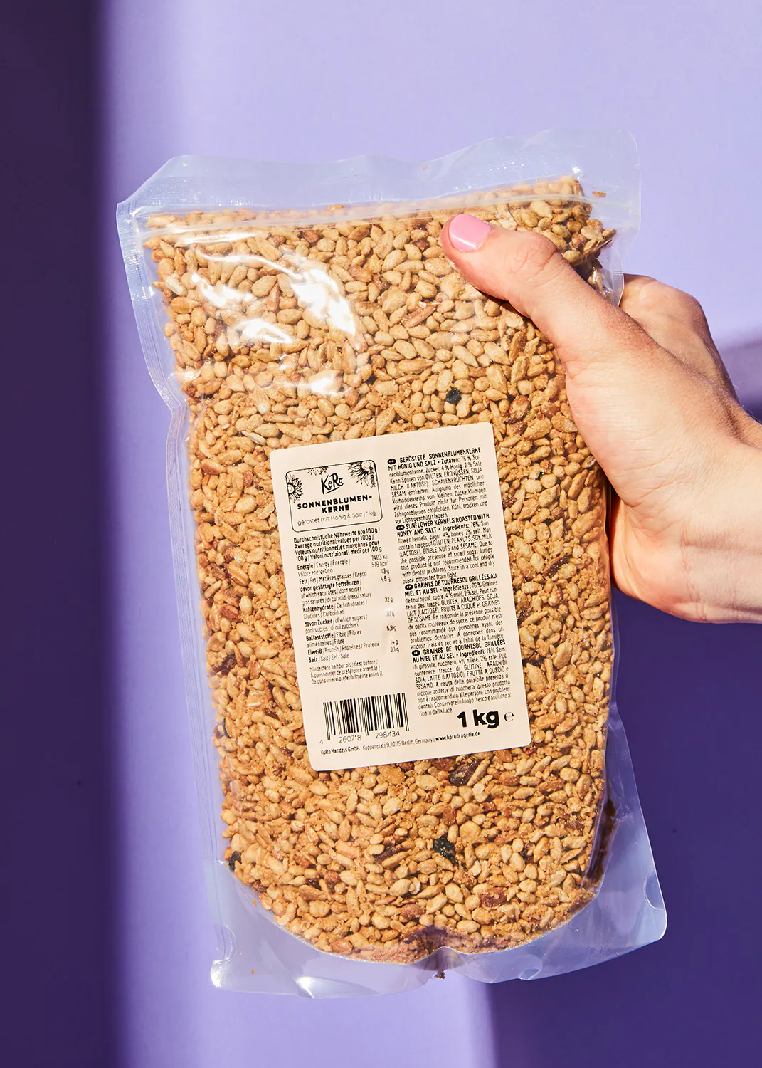 une personne tient un sac de graines de sésame avec une étiquette qui dit 1 kg