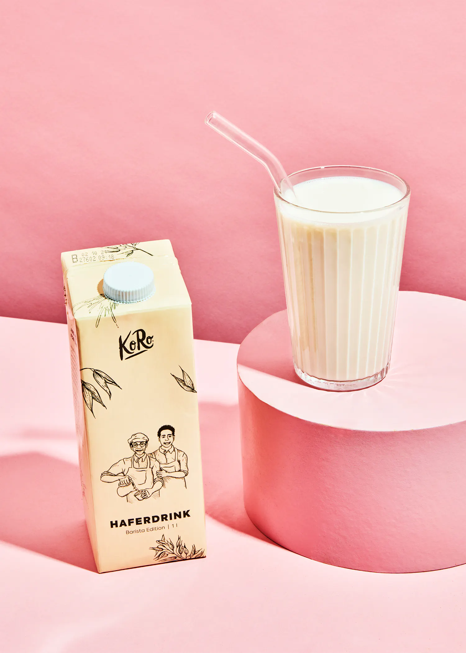 une boîte de boisson d' avoine avec une paille à côté d' un verre de boisson d' avoine