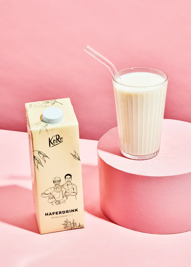 une boîte de boisson d' avoine avec une paille à côté d' un verre de boisson d' avoine