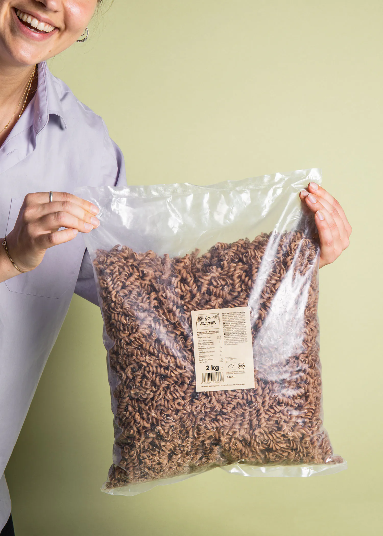 une femme tient un sac en plastique de pâtes brunes