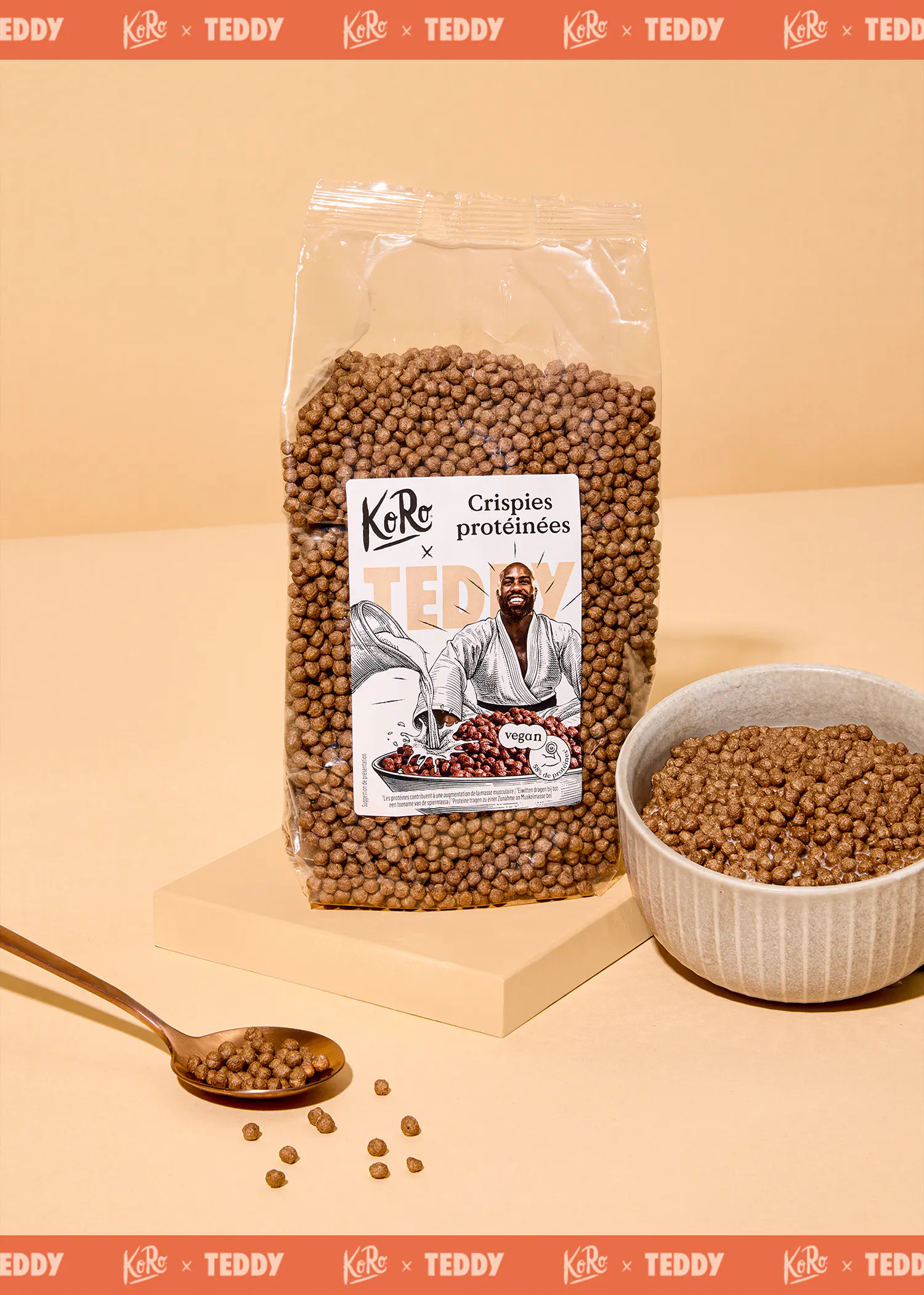 un sac de crispies protéinées véganes koro x teddy est posé sur une surface beige, à côté d'un bol rempli des mêmes crispies et d'une cuillère avec quelques crispies.