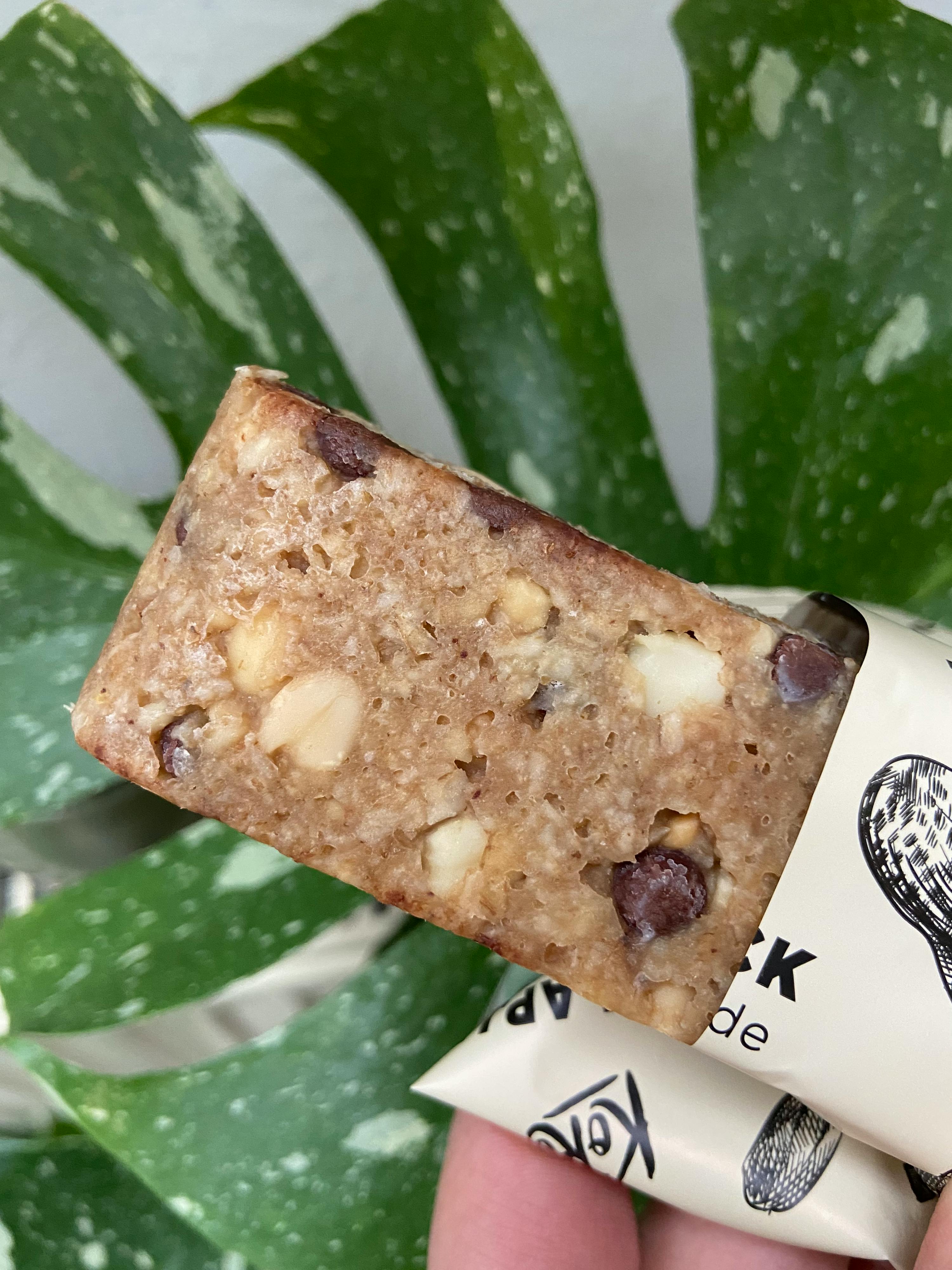 una persona tiene in mano una barretta di arachidi con gocce di cioccolato