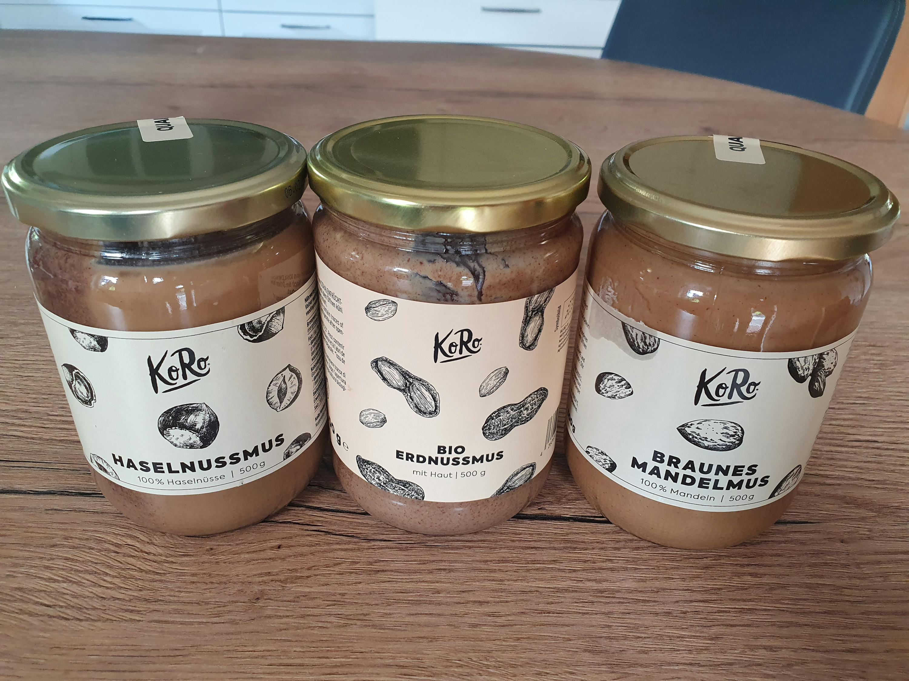 trois bocaux de pâte à tartiner sur une table en bois