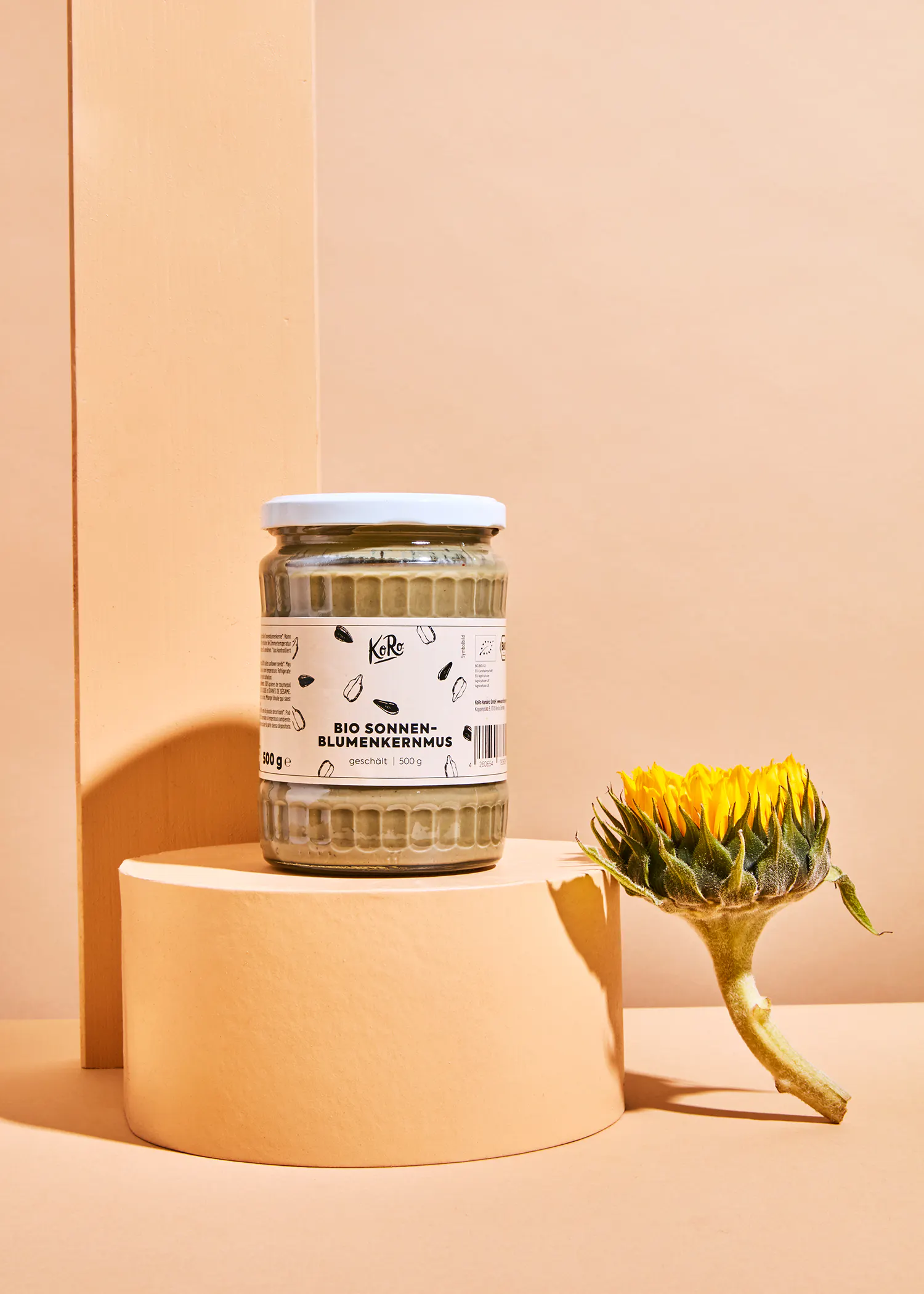 ein Glas Sonnenblumenkernmus steht neben einer Sonnenblume