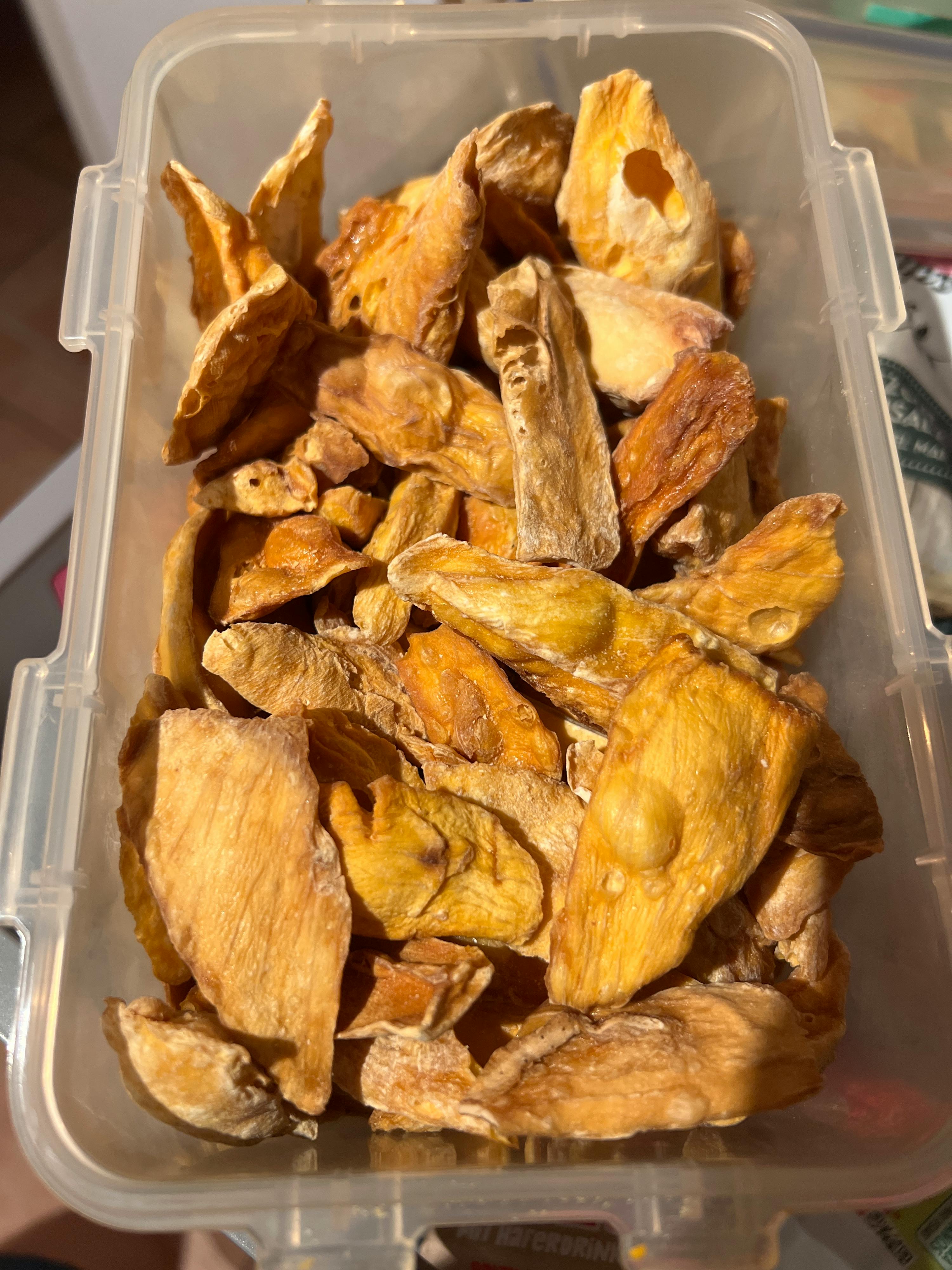 a clear plastic container filled with dried pineapple slices