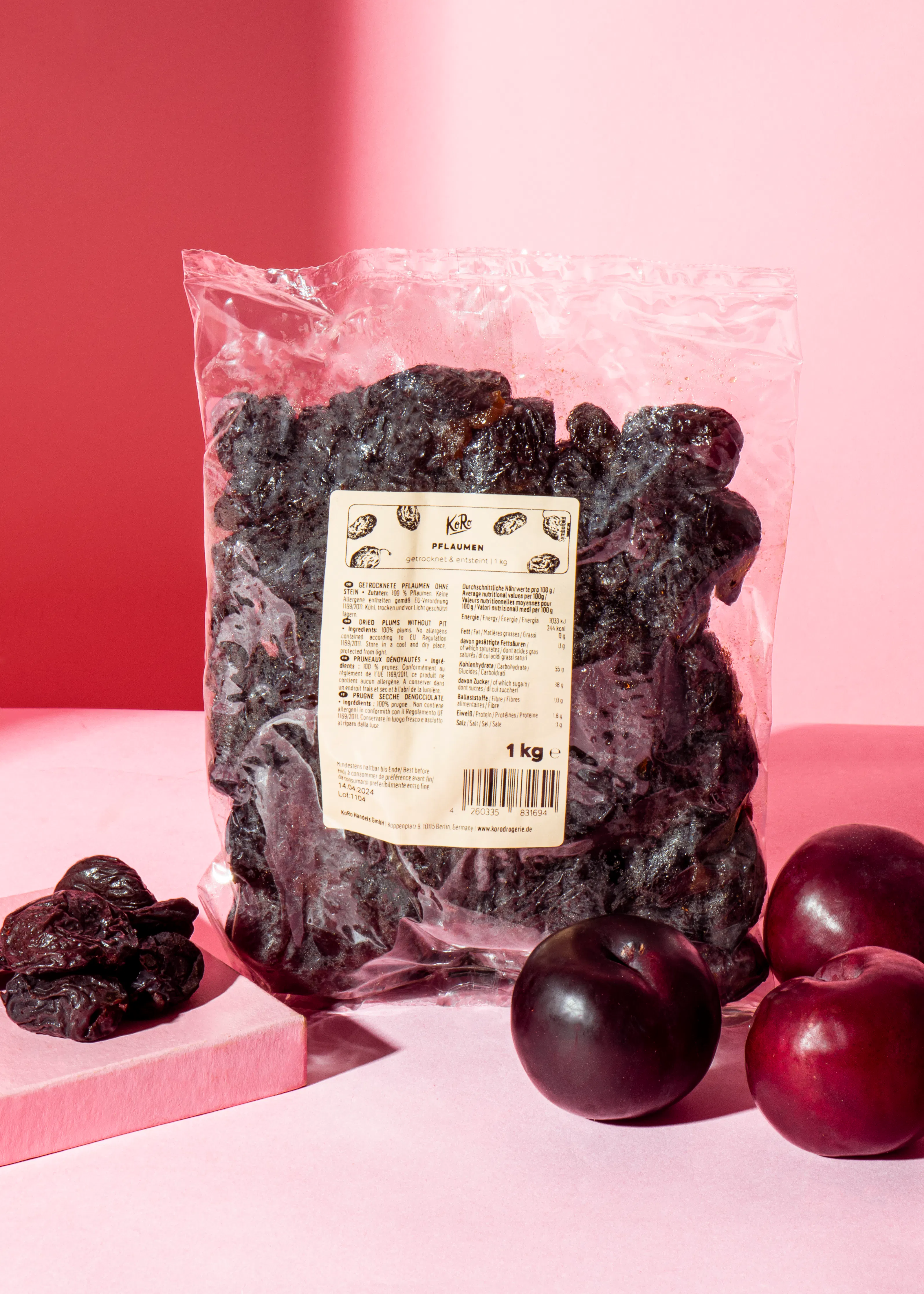 un sac de prunes séchées est assis sur une table rose