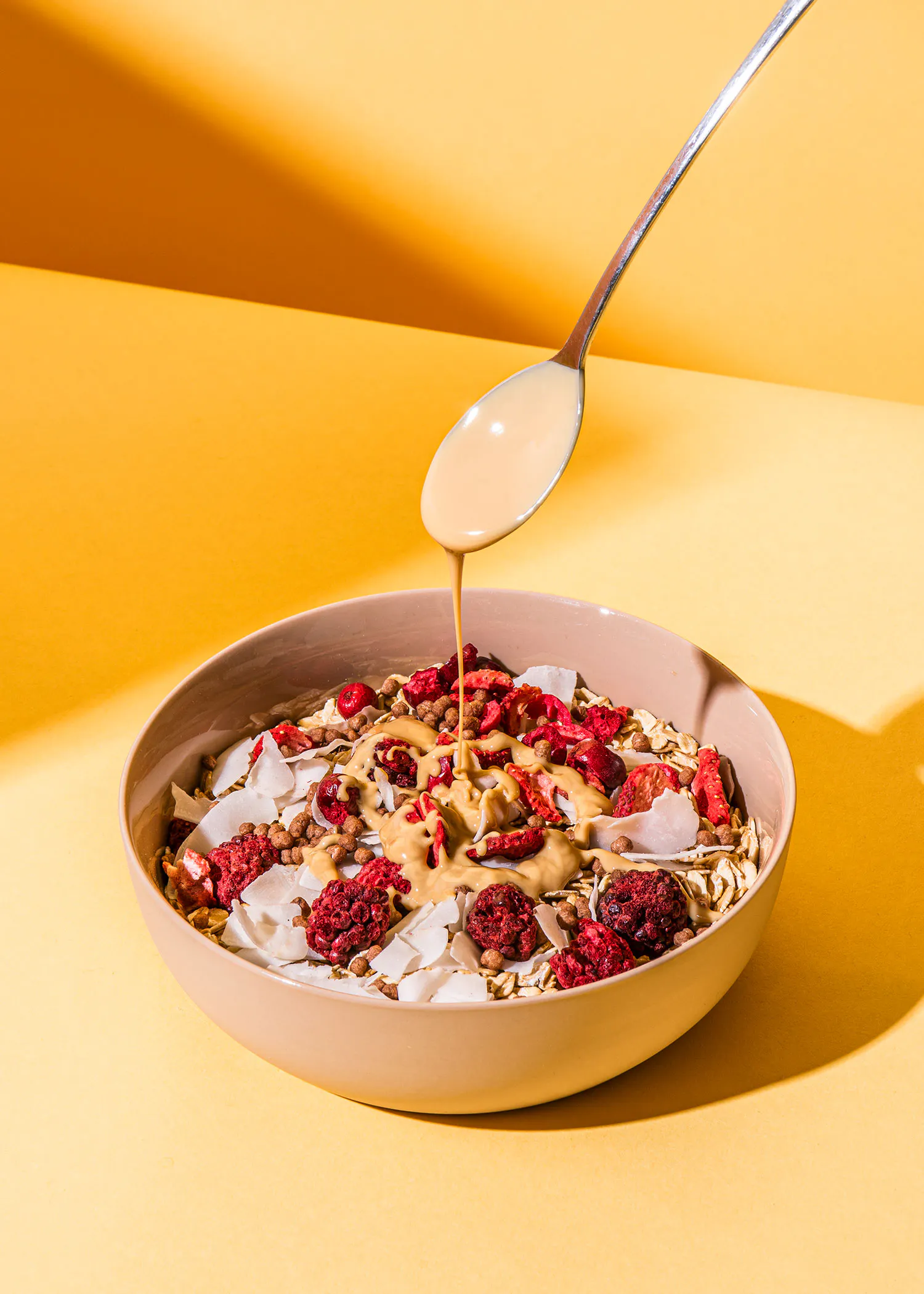 eine Schüssel Haferflocken mit Erdnussbutter und Himbeeren wird mit einem Löffel gegossen