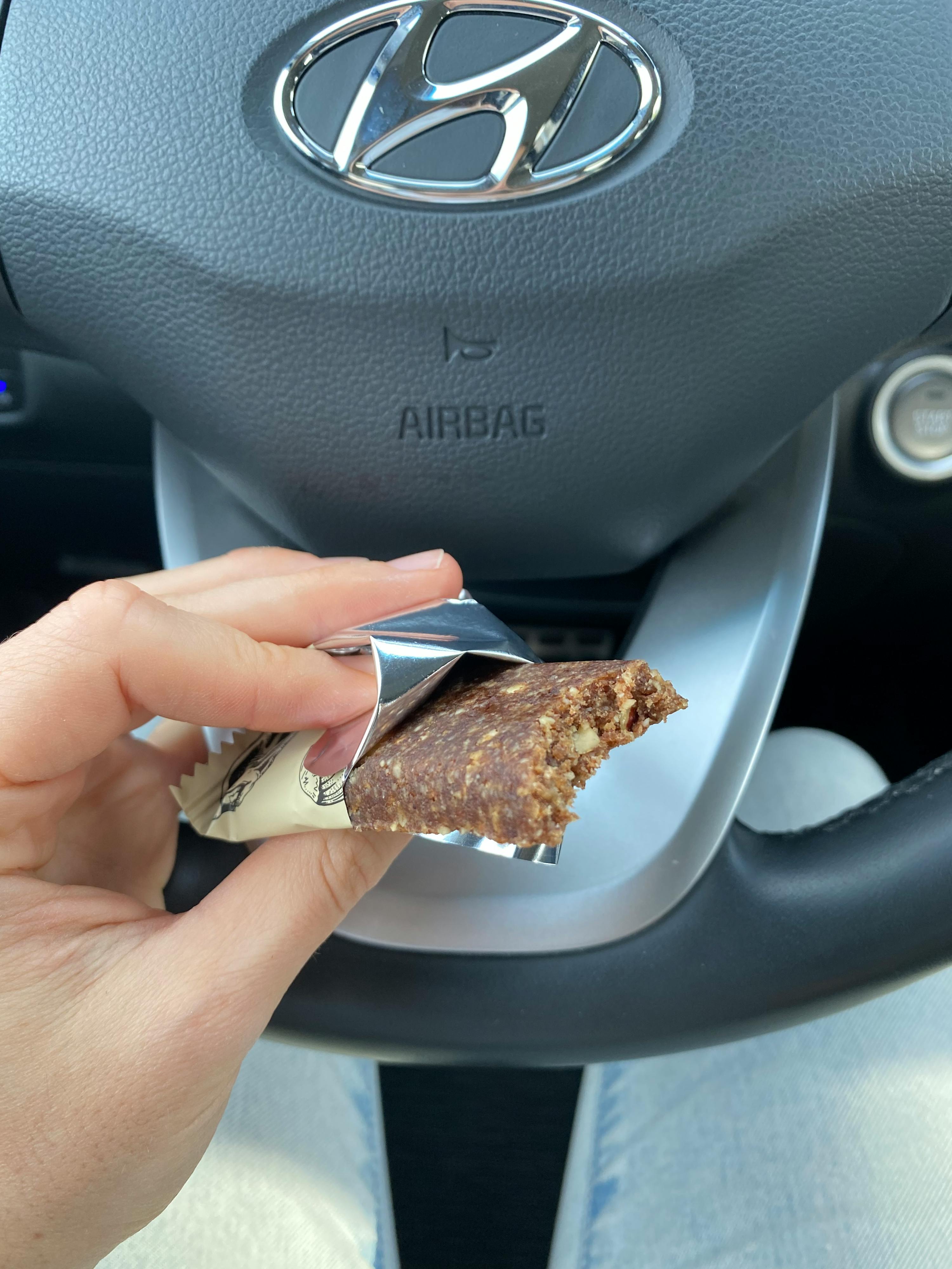 une personne tient une barre de chocolat à côté d' un volant d' une hyundai