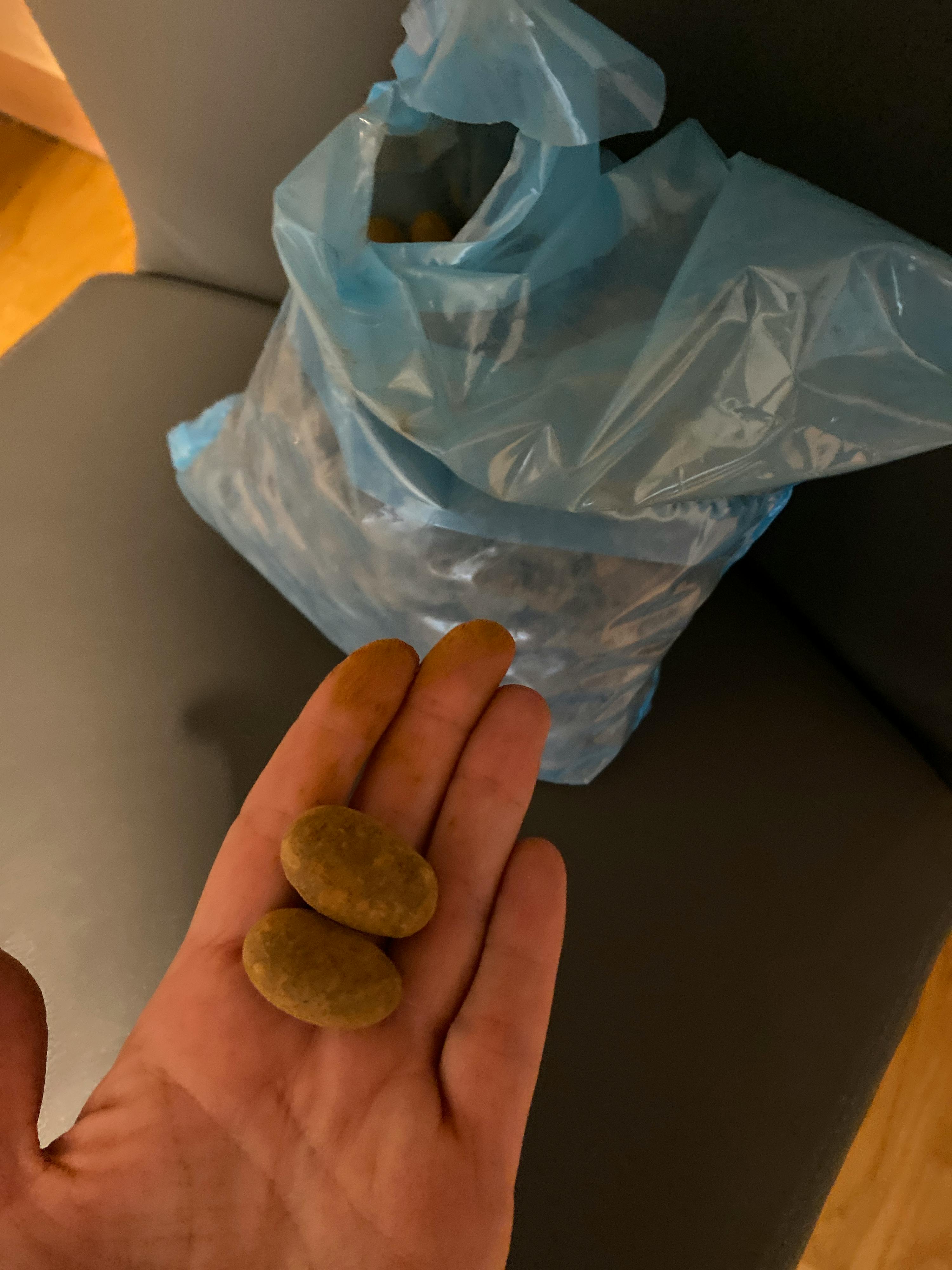 eine Person hält zwei braune Münzen in der Hand neben einer Plastiktüte