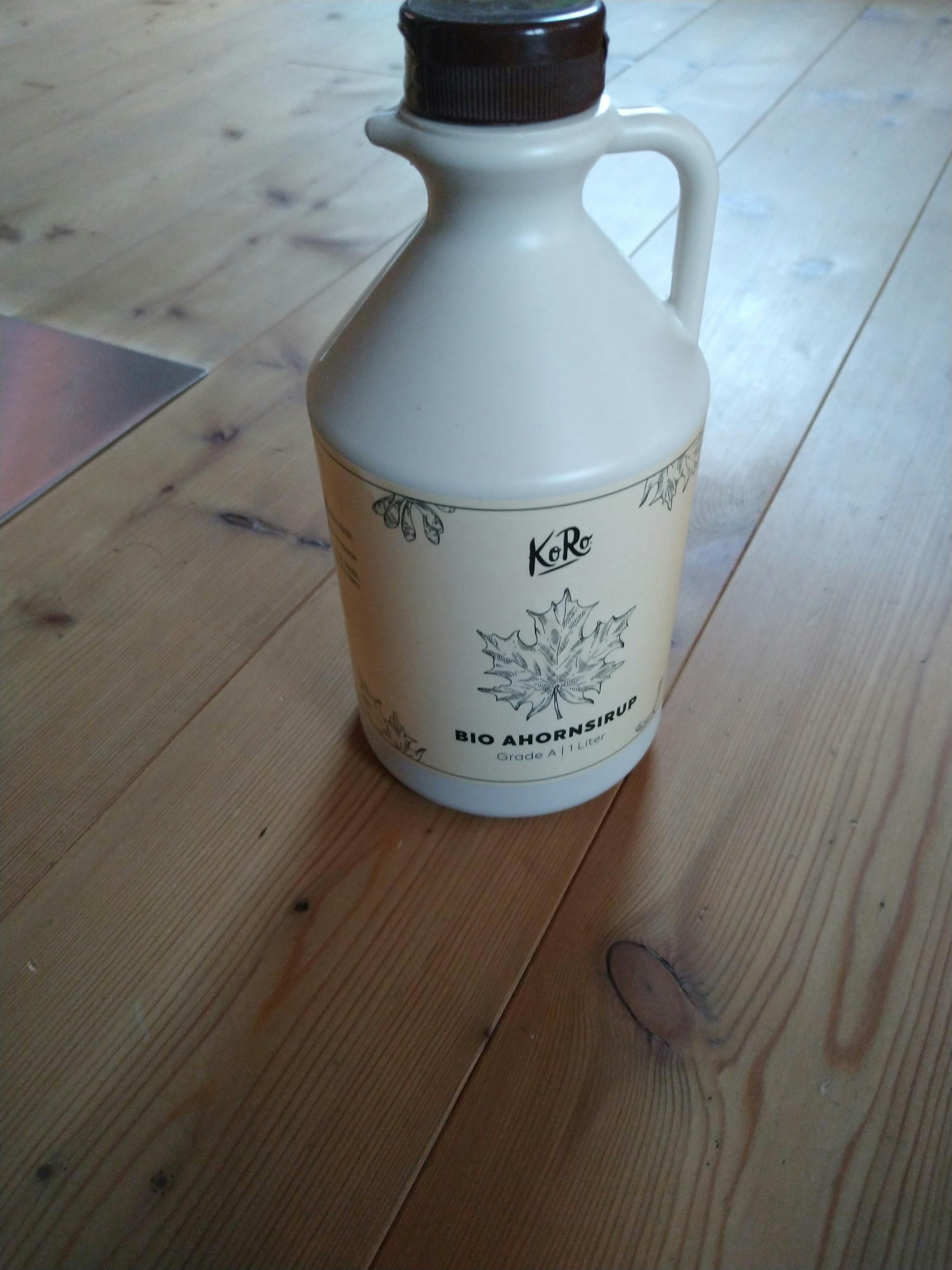 eine weiße Flasche auf einem Holzboden mit der Aufschrift bio-ahornsirup