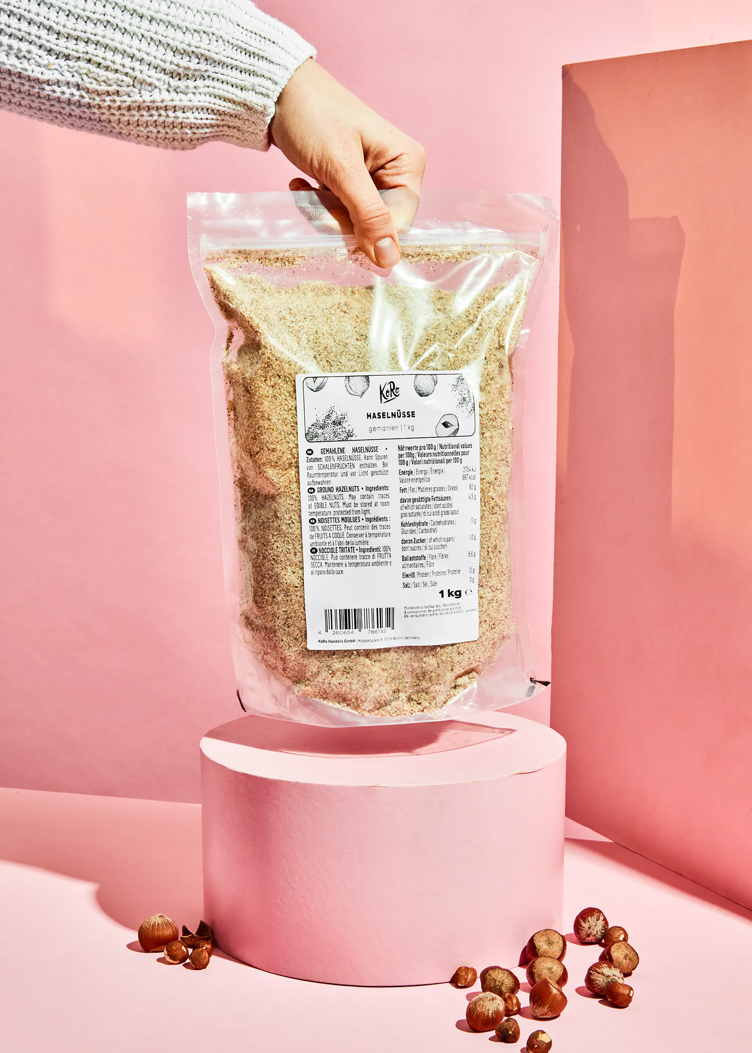 une personne tient un sac de farine de noisettes à côté de noisettes