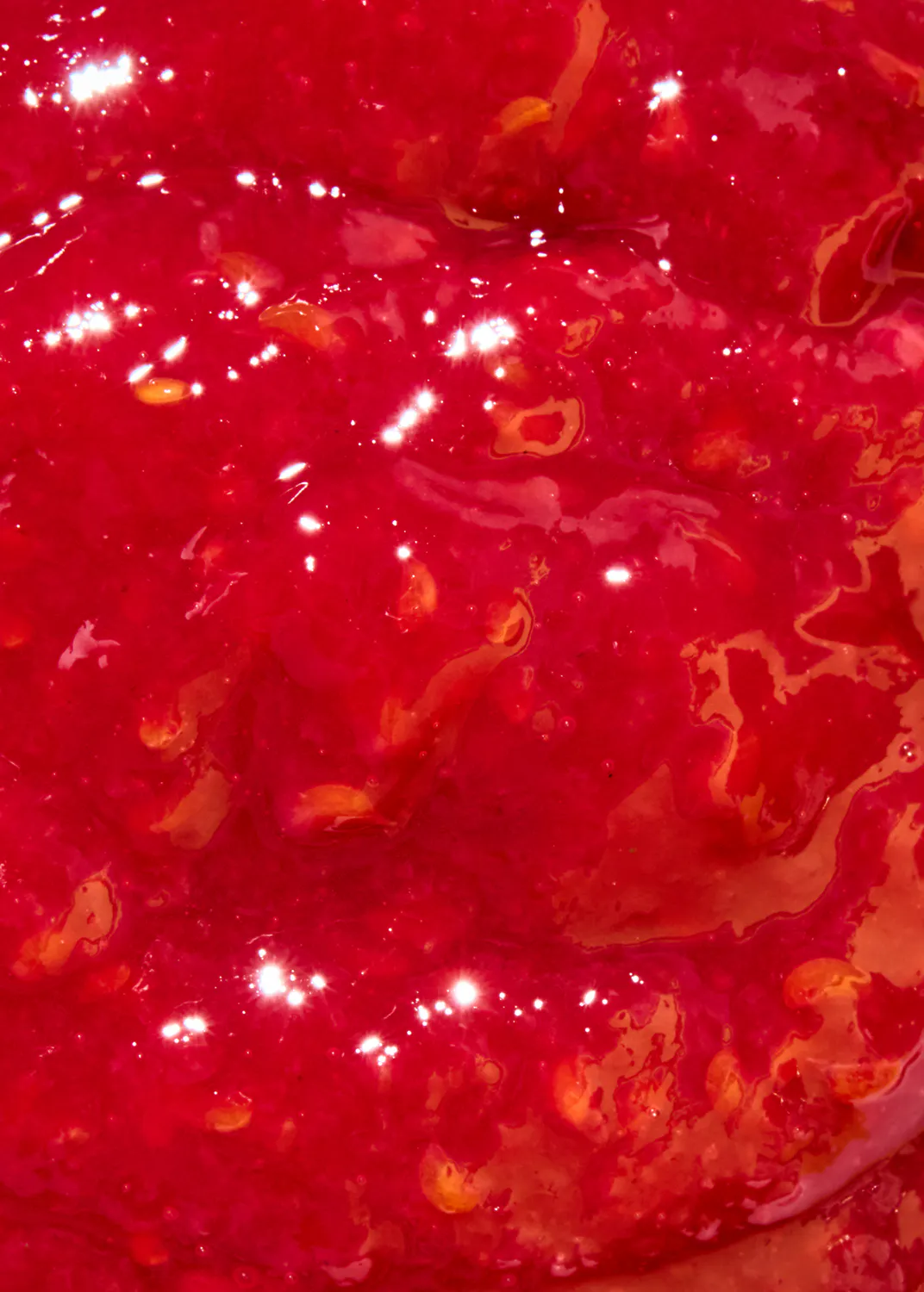 un gros plan d' un liquide rouge avec des gouttes d' orange