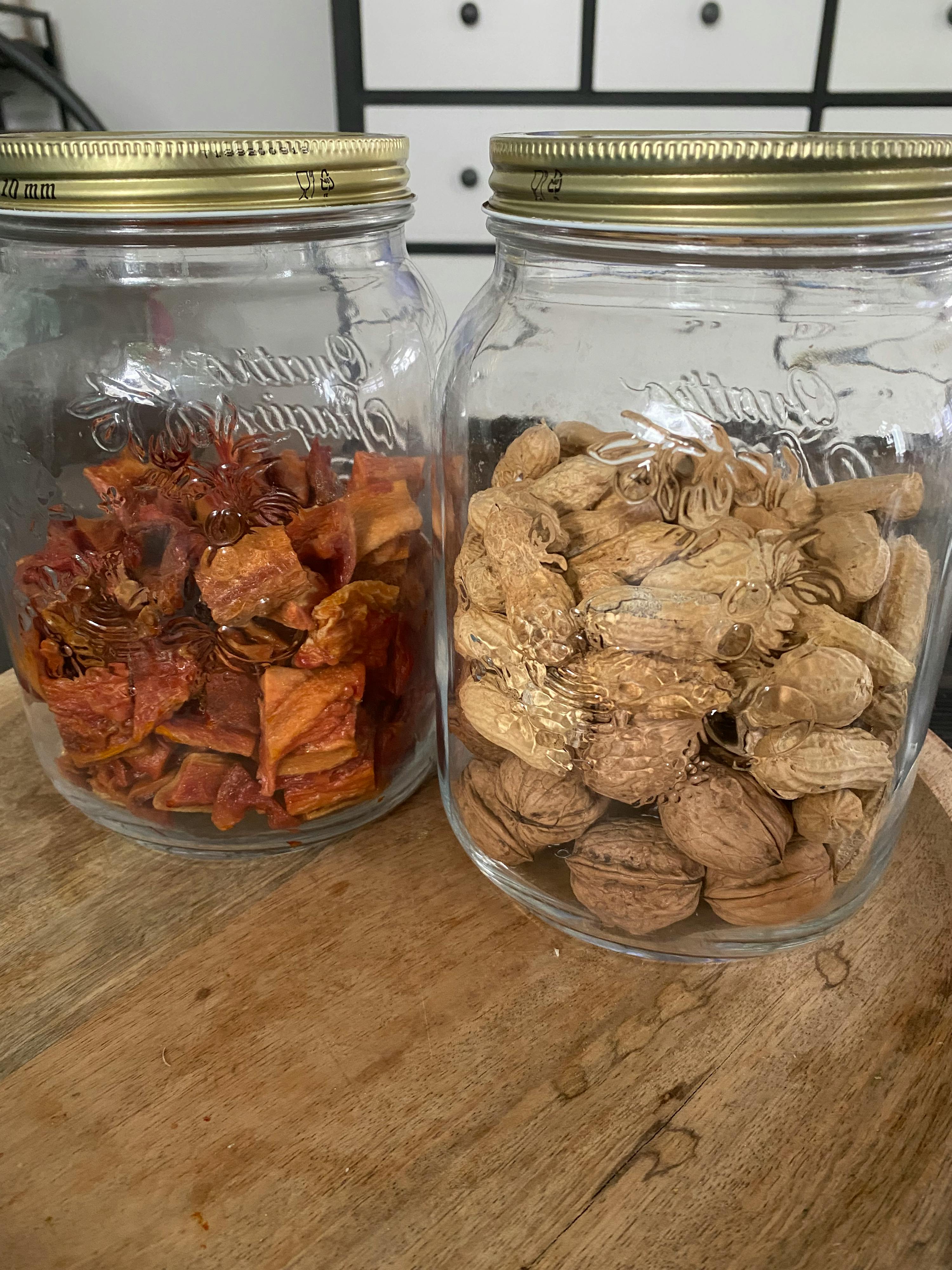 deux bocaux en verre remplis de noix et de pommes séchées