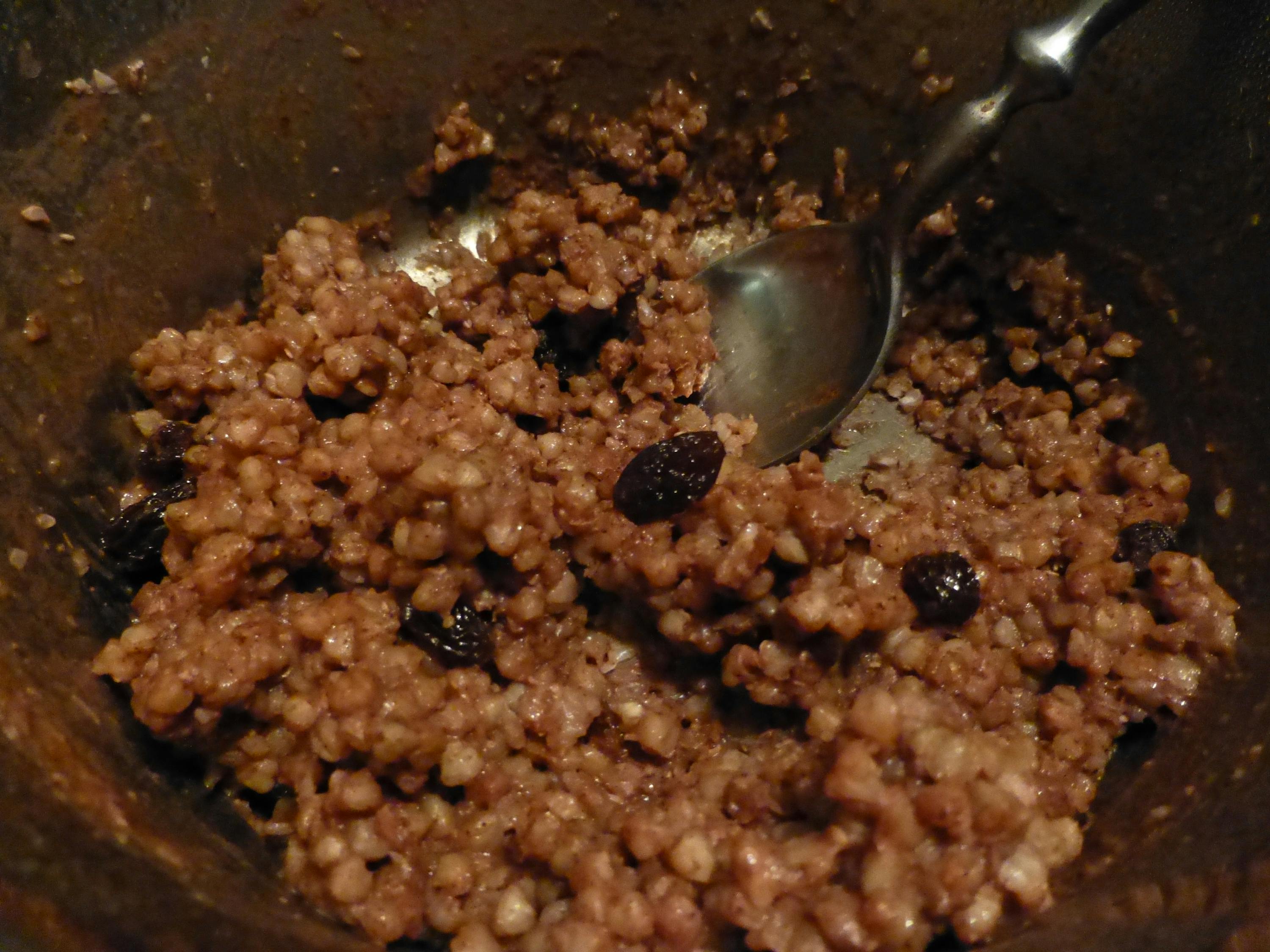a bowl of food with raisins and a spoon