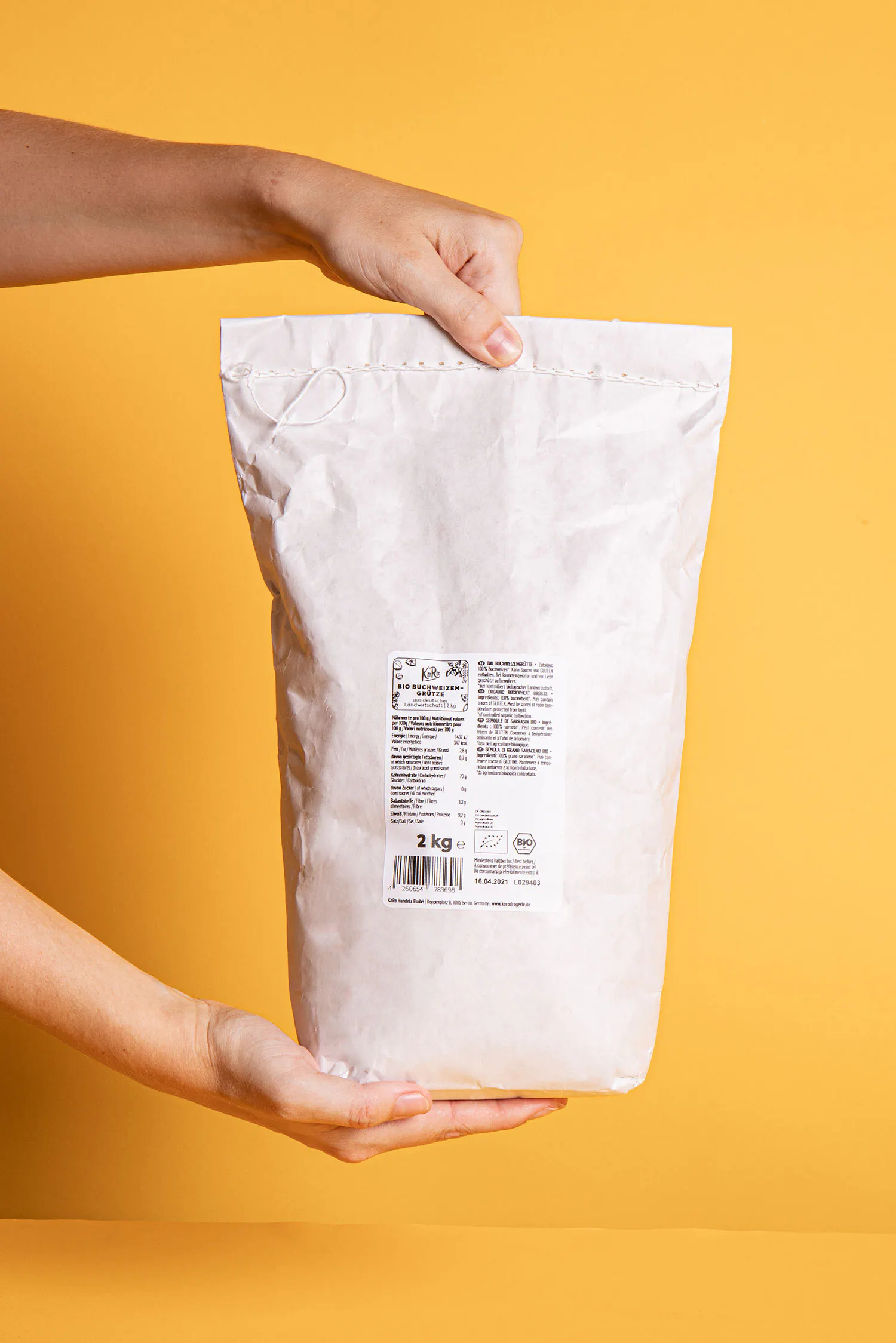 une personne tient un sac de farine de 2 kg dans ses mains