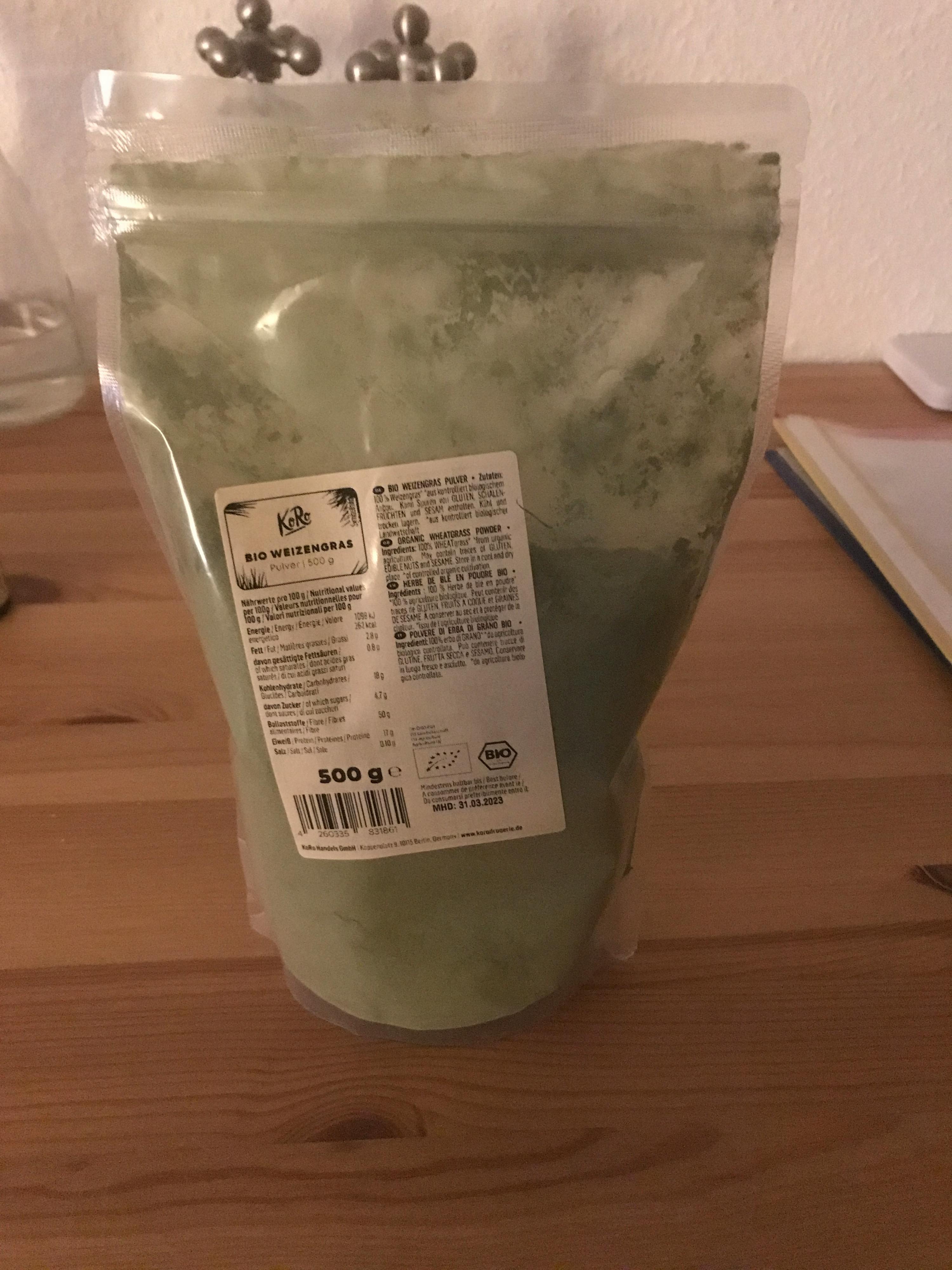 un sac de poudre verte est assis sur une table en bois