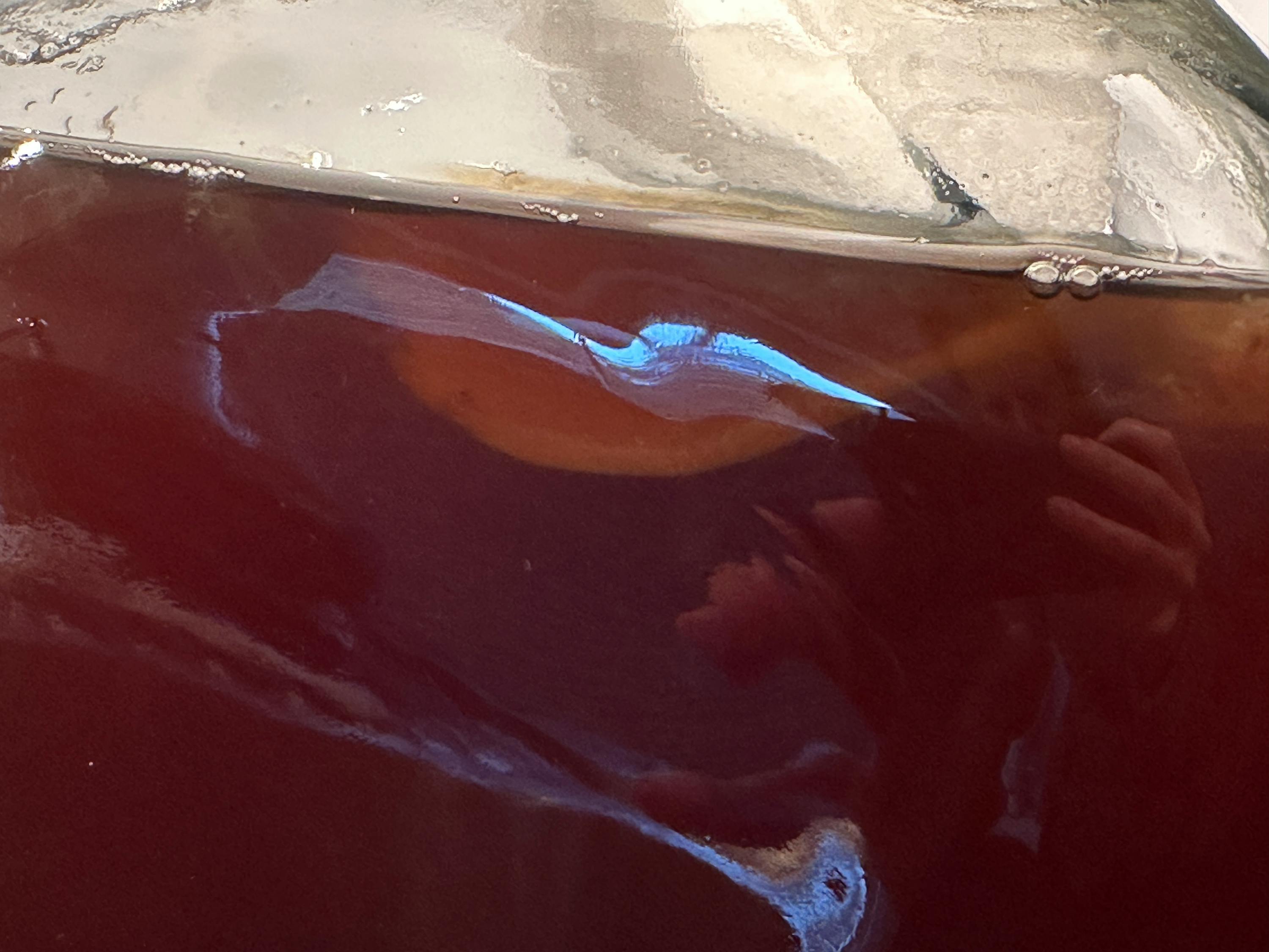 a person is taking a picture of their reflection in a bottle of liquid