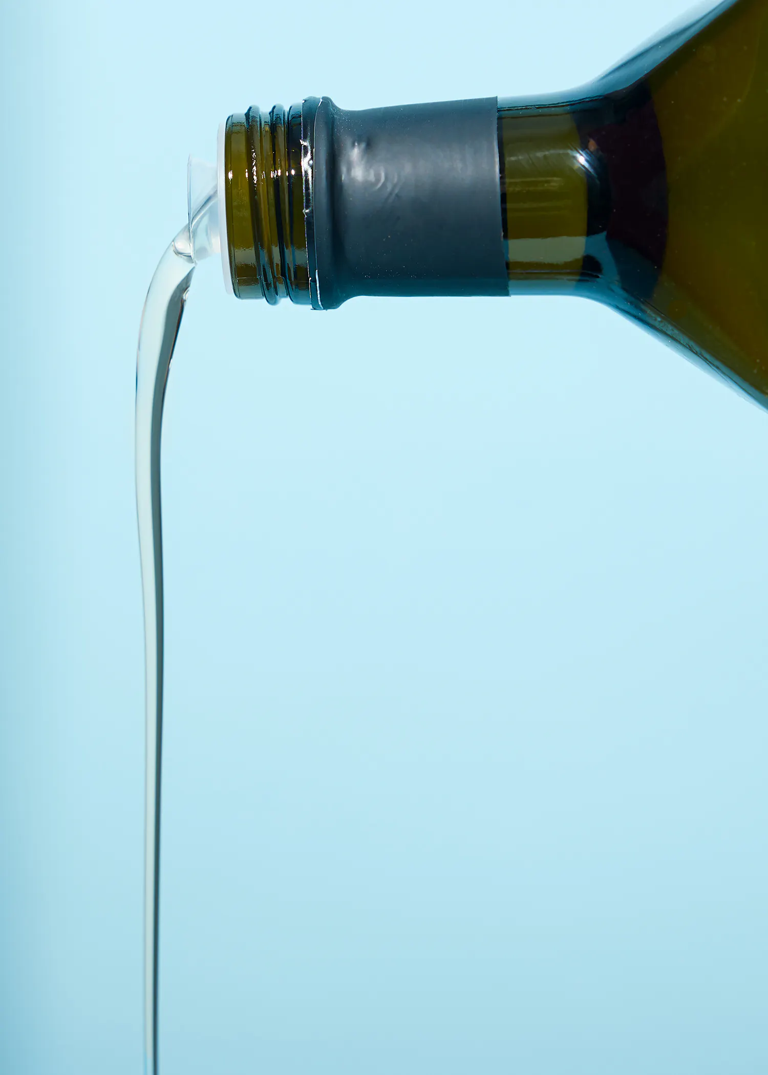 l' huile est versée d' une bouteille sur fond bleu